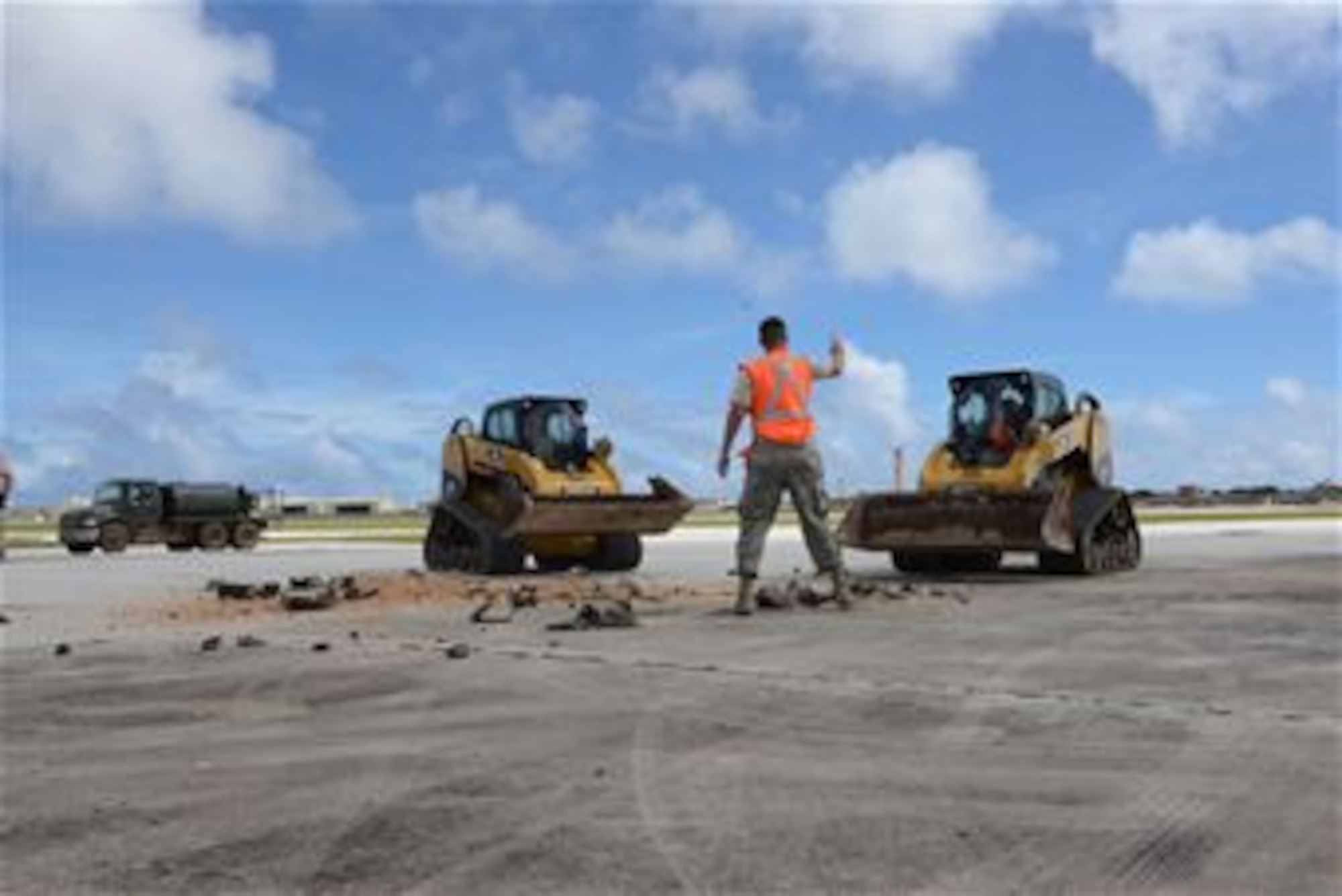 Staff Sgt. Austin Winegardner, 36th Civil Engineer Squadron project leader, directs Airmen operating heavy machinery to clear debris away from a simulated damaged area created during airfield damage repair training on the Andersen Air Force Base, Guam, flightline Jan. 23, 2014. The 36th Civil Engineer Squadron Airmen were the first in the Air Force to receive training on a new airfield damage repair capability.  (U.S. Air Force photo by Airman 1st Class Emily A. Bradley/Released)