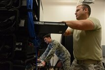 (From right) Staff Sgt. Richard Rawls, cyber systems supervisor, and Senior Airman Garett Savard, cyber systems operator, both from the 644th Combat Communications Squadron, update programs on one of the three transportable base servers Jan. 13, 2014, on Andersen Air Force Base, Guam. The 644th CBCS is continuously ready to deploy anything from a small detail consisting of two Airmen and a laptop, to a package that can provide up to three bases full communications support. (U.S. Air Force photo by Airman 1st Class Emily A. Bradley/Released)