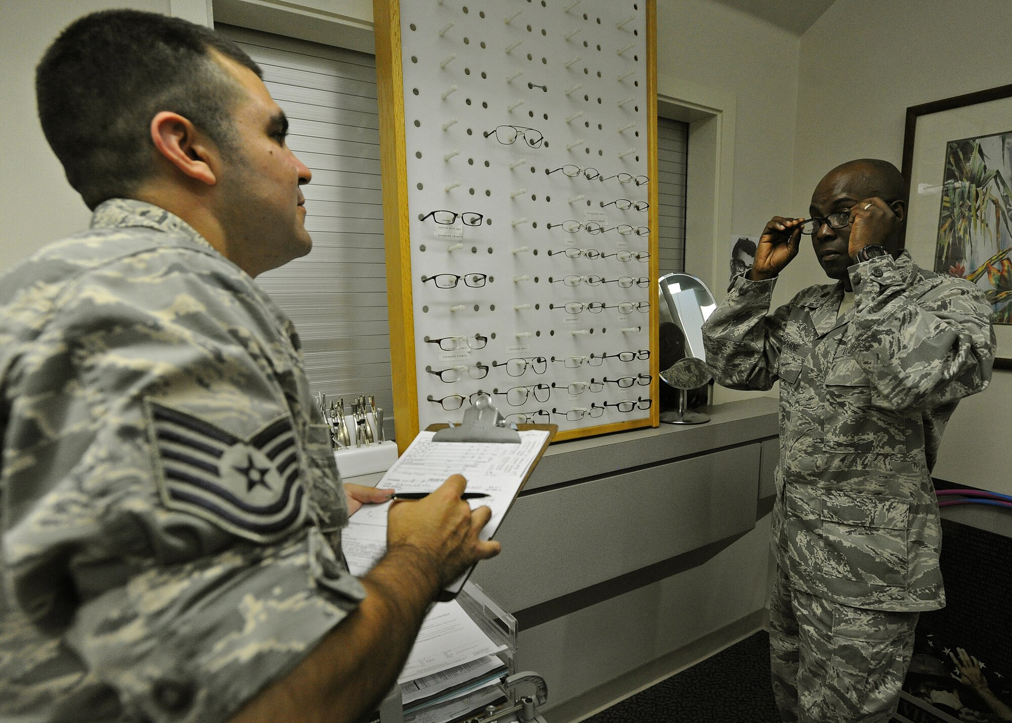 Tech. Sgt. Anthony Vara, 15th Medical Group Optometry Element NCO in charge, left, helps Maj. Callistus Elbourne, Pacific Air Forces Air Postal Squadron commander, right; select a pair of glasses during a routine eye exam at the optometry clinic on Joint Base Pearl Harbor-Hickam, Hawaii, Feb. 24, 2014. The Hickam eye clinic offers the G-Eyes program, which is a unique system that allows Soldiers, Sailors, Airmen and Marines in deployed locations to reorder prescription glasses, gas mask inserts, military combat eye protection and prescription lenses directly from the internet. (U.S. Air Force photo/Master Sgt. Jerome S. Tayborn)