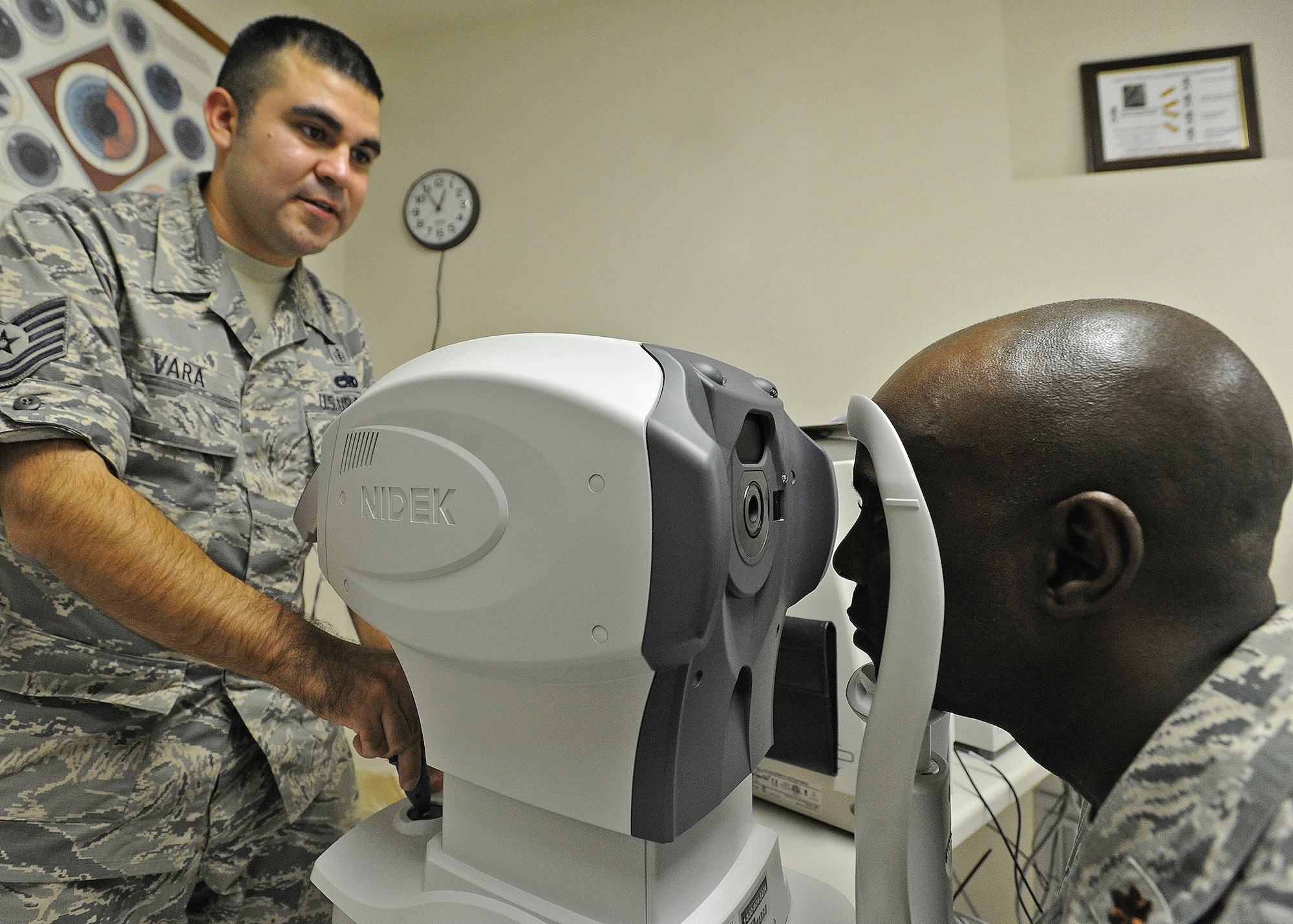 Tech. Sgt. Anthony Vara, 15th Medical Group Optometry Element NCO in charge, left, examines the eyes of Maj. Callistus Elbourne, Pacific Air Forces Air Postal Squadron commander, right, during a routine eye exam at the optometry clinic on Joint Base Pearl Harbor-Hickam, Hawaii, Feb. 24, 2014. To maintain good eyesight between optometry visits, people should wear sunglasses that provide 100% ultraviolet protection when outdoors and avoid cigarette smoke. (U.S. Air Force photo/Master Sgt. Jerome S. Tayborn)