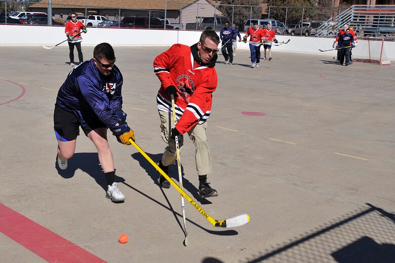 PETERSON AIR FORCE BASE, Colo. -- Staff Sgt. Danny Kuertz (left) fights Sgt. Dwayne Desveaux (right) over the ball during the USA vs. Canada Ball Hockey Tournament at Peterson Air Force Base Feb. 21. Canada won this game 7-4. The tournament was a best of three series between teams made up of junior Airmen, junior leadership and senior leadership. Team Canada won the first two games and the series with scores of 6-0 in the junior enlisted game and 7-4 in the junior leadership game. Team USA avoided a shutout by defeating Team Canada in the senior leadership game 6-2. (U.S. Air Force photo/Dennis Howk)