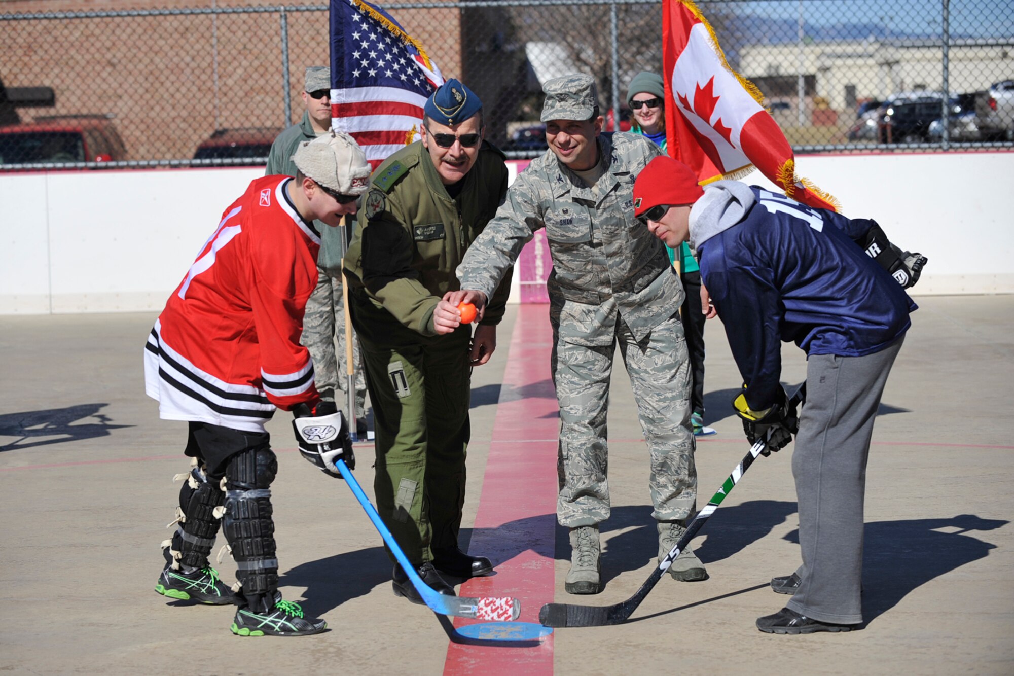 PETERSON AIR FORCE BASE, Colo. -- Maj. Gen. Andre Viens of NORAD/NORTHCOM and Col. John Shaw, 21st Space Wing commander, drop the ball to start the USA vs. Canada Ball Hockey Tournament at Peterson Air Force Base Feb. 21. The tournament was a best of three series between teams made up of junior Airmen, junior leadership and senior leadership. Team Canada won the first two games and the series with scores of 6-0 in the junior enlisted game and 7-4 in the junior leadership game. Team USA avoided a shutout by defeating Team Canada in the senior leadership game 6-2. (U.S. Air Force photo/Robb Lingley)