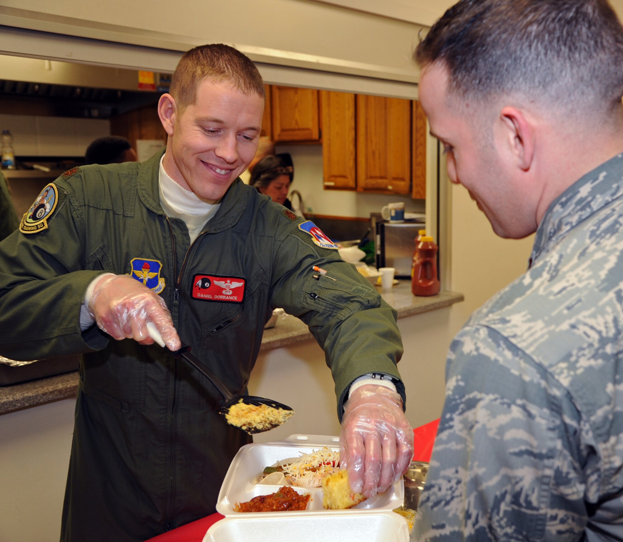 Maj. Daniel Dorrance, an 8th Flying Training Squadron instructor pilot, serves a slice of jalapeno cornbread during the February Singles’ International Gourmet Meal Opportunity, Feb. 24, in the Community Chapel Activity Center at Vance Air Force Base, Okla.  (U.S. Air Force photo/ Senior Airman Frank Casciotta)