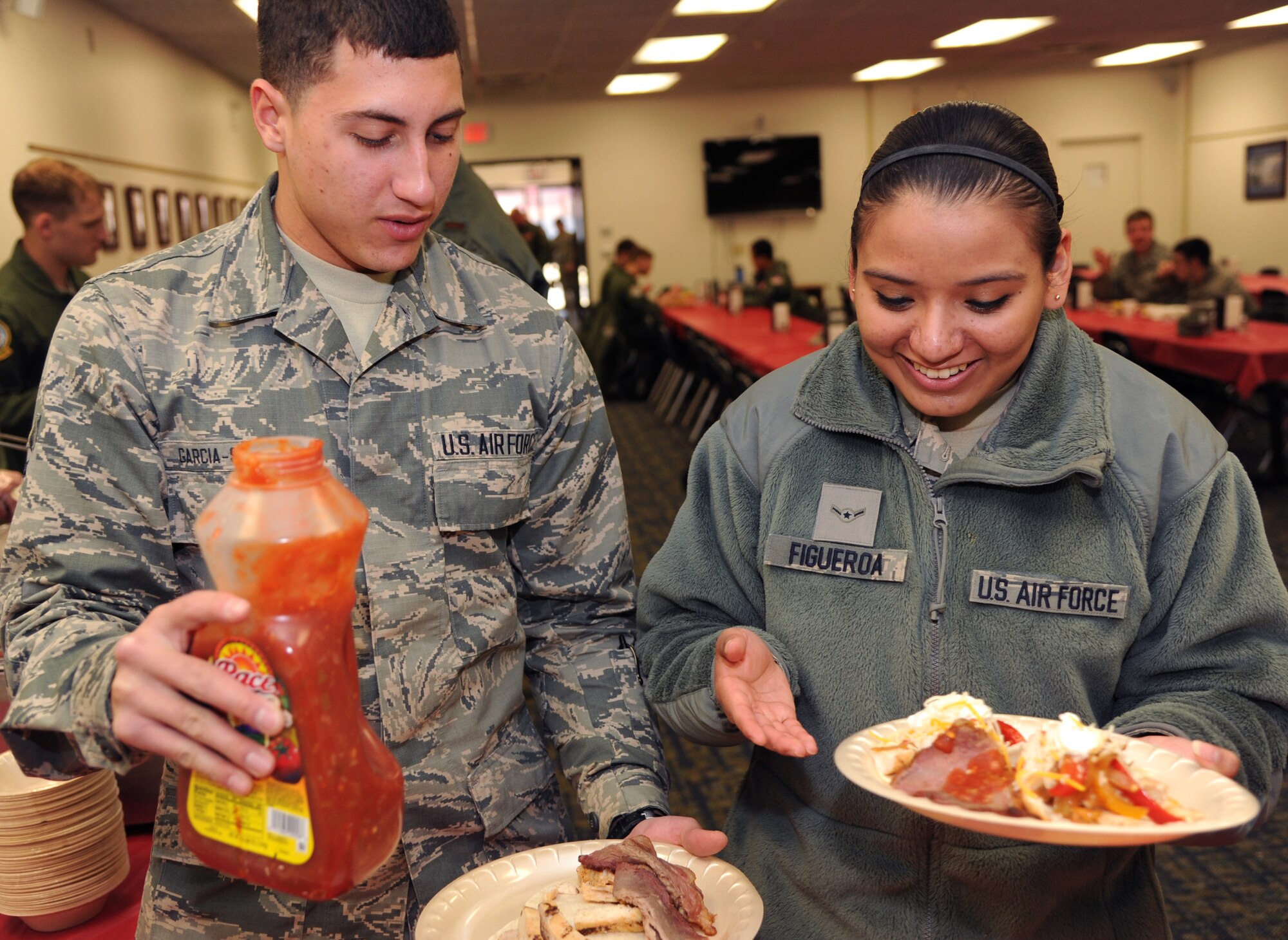 Airman 1st Class Eduardo Garcia-Santiago, left, and Airman 1st Class Nancy Figueroa, both 71st Comptroller Squadron customer-service technicians, dress their fajitas during the February Singles’ International Gourmet Meal Opportunity, Feb. 24, in the Community Chapel Activity Center at Vance Air Force Base, Okla. (U.S. Air Force photo/ Senior Airman Frank Casciotta)