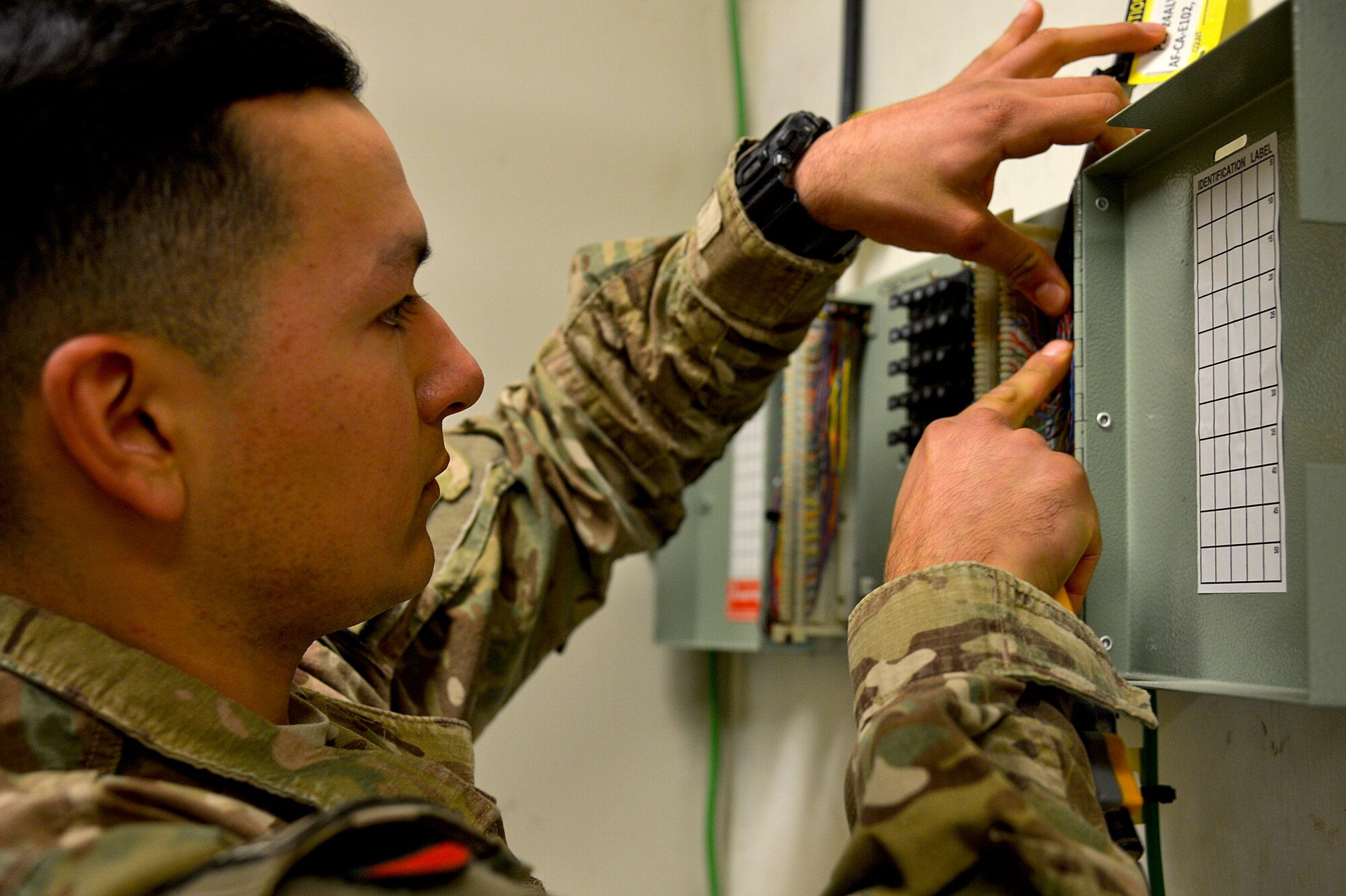 U.S. Air Force Senior Airman Abraham Pulido, 455th Expeditionary Communications Squadron cable and antenna maintenance, connects wires at Bagram Airfield, Afghanistan, Feb. 24, 2014. 455th ECS Airmen are responsible for getting all of the network connectivity in a new building. (U.S. Air Force photo by Senior Airman Kayla Newman/Released)