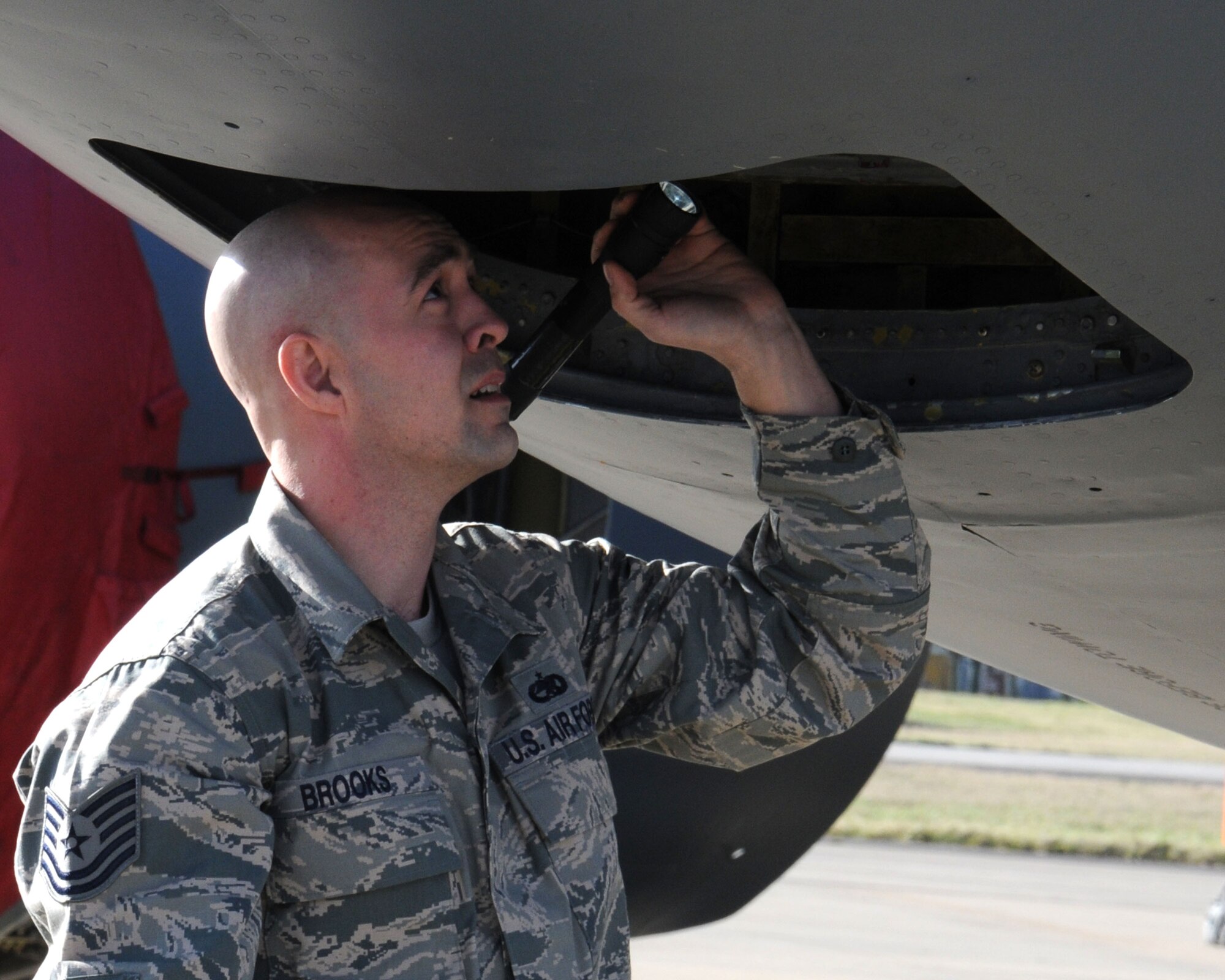 U.S. Air Force Tech. Sgt. Shannon Brooks, 100th Aircraft Maintenance Squadron production expeditor from Folio, Calif., inspects the lower nose compartment for discrepancies during an aircraft preflight inspection Feb. 19, 2014, on RAF Mildenhall, England. Brooks improved the wash rack program by establishing a team structure, ensuring the wash teams had transportation and adequate tools, and he implemented a 30-day wash cycle. After a wash, the team ensures the components are properly lubricated and push out any water or foreign materials. (U.S. Air Force photo by Gina Randall/Released)