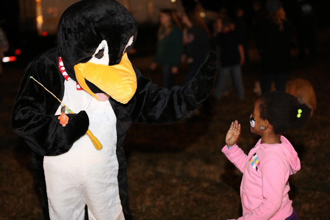 A child high-fives Chili the Penguin, mascot for the Snow Up The Park event at the Swansboro Municipal Park, Feb. 21. More than two tons of snow were created to make sledding slopes and a play area available to the attendees. 
