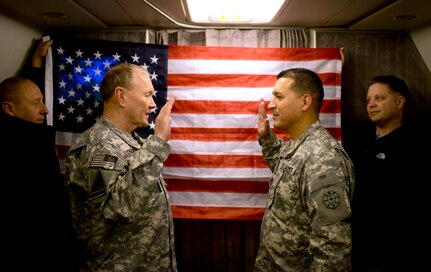 Gen. Martin E. Dempsey, chairman of the Joint Chiefs of Staff, reenlist Sgt 1st Class Gary Garcia for 6 more years in the US army prior to taking off from Bagram Air Base, Afghanistan, Feb. 26, 2014.