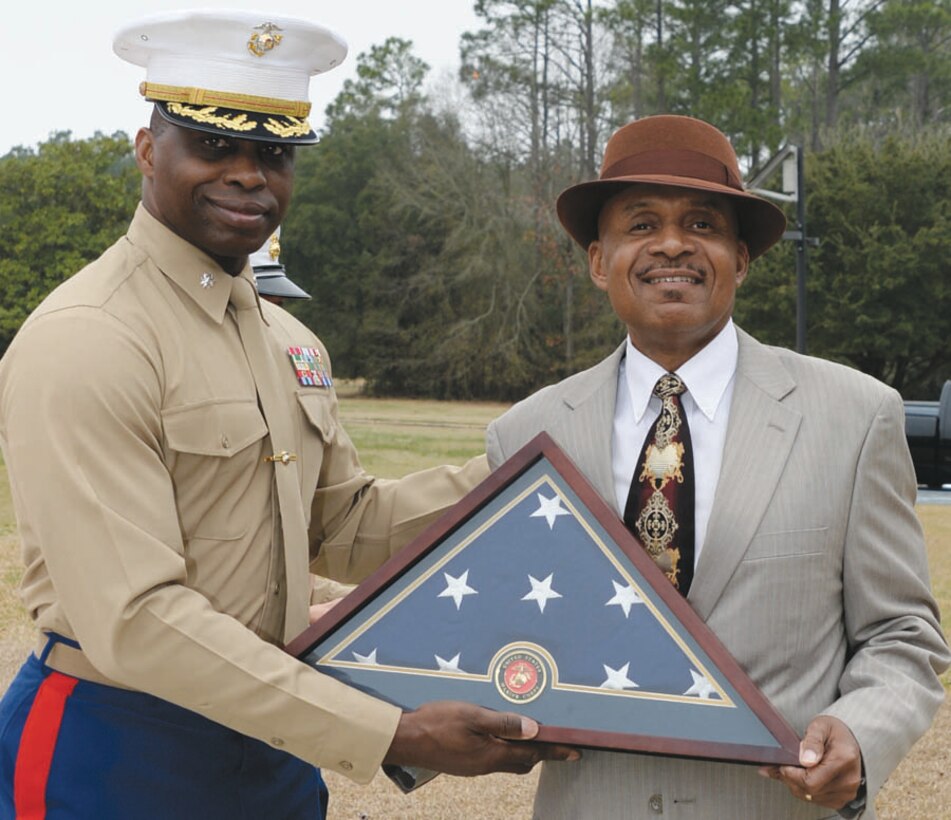 Lt. Col. George Lampkin, operations officer, C4, Marine Corps Logistics Command, presents Bennie Paige an American flag during his retirement ceremony held in front of Building 3700, Feb. 20. Paige retired after 37 years of service and the flag was flown in his honor.