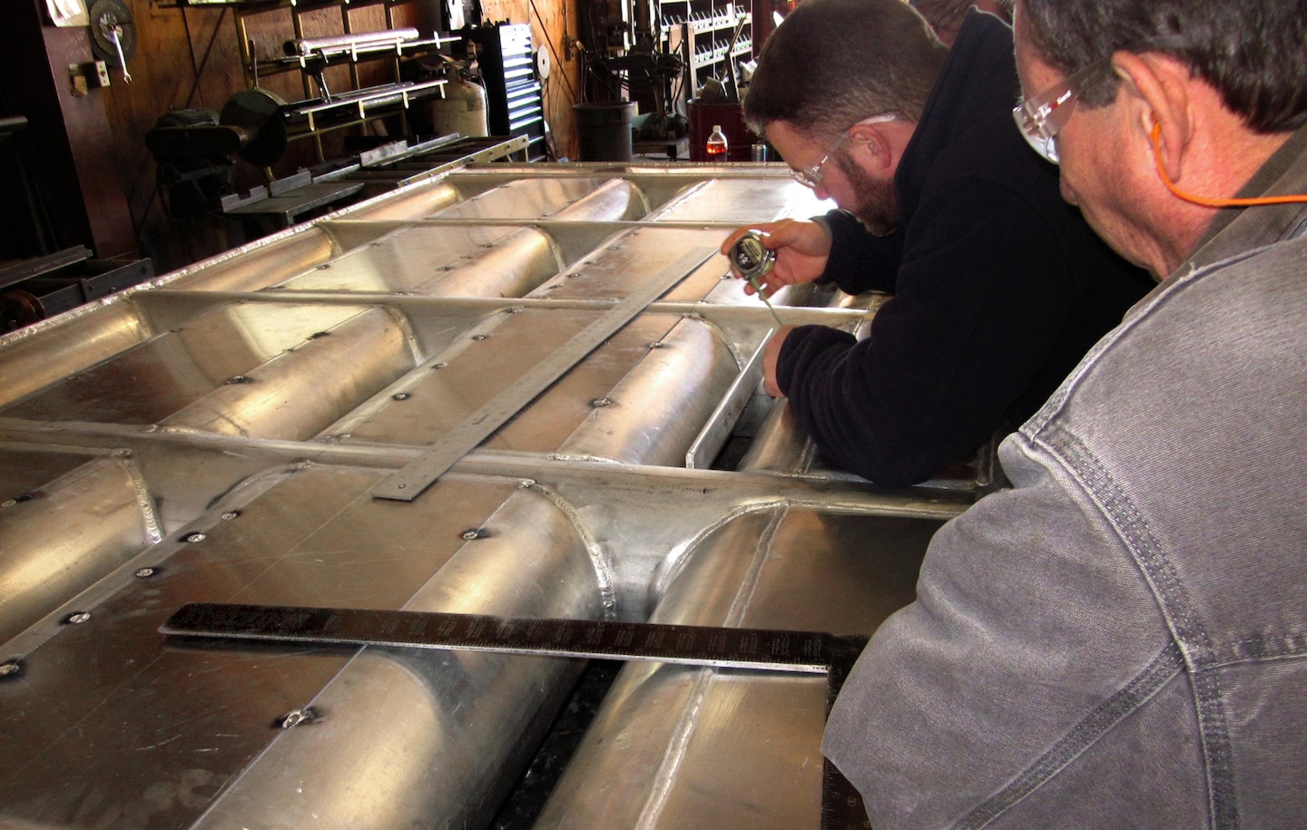 NOAA Fisheries Biologist Trevor Conder and Bart Bartelme, fabrication sub-contractor at Waite Specialty Machine in Longview, Wash., ensure the exclusion bars welded in front of each entrance orifice of the prototype lamprey-passage structure meets minimum-clearance specifications to allow lampreys through, but prevent salmon and steelhead from attempting to enter and possibly getting stuck.