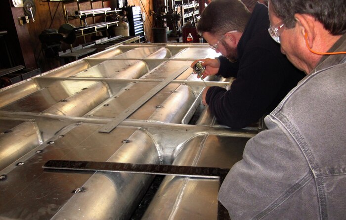 NOAA Fisheries Biologist Trevor Conder and Bart Bartelme, fabrication sub-contractor at Waite Specialty Machine in Longview, Wash., ensure the exclusion bars welded in front of each entrance orifice of the prototype lamprey-passage structure meets minimum-clearance specifications to allow lampreys through, but prevent salmon and steelhead from attempting to enter and possibly getting stuck.