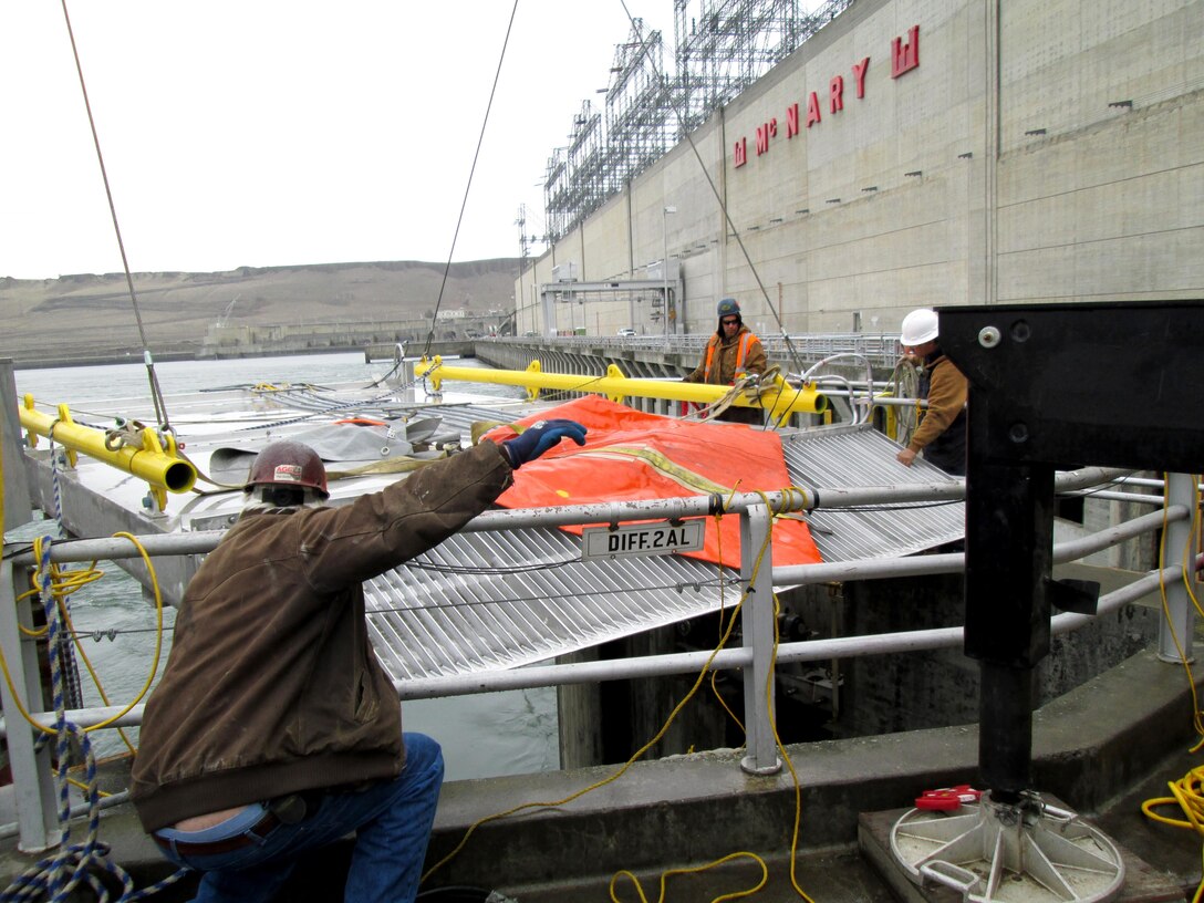 Crane operators lower the upstream baffle box and trash rack sections of McNary Lock and Dam’s prototype lamprey-passage structure into the Oregon shore fish ladder.