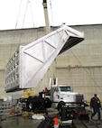 It takes a team of riggers and a strong crane to lower the entrance hood of McNary Lock and Dam’s prototype lamprey-passage structure  into the Oregon shore fish ladder. 
