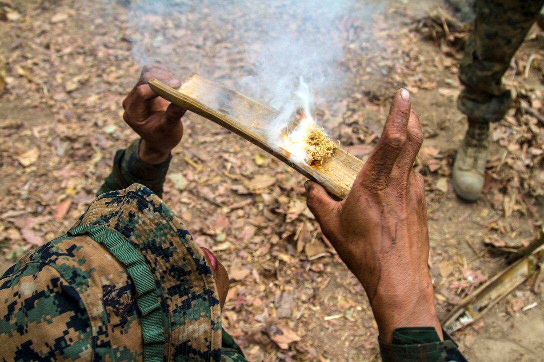 A Royal Thai Reconnaissance Marine blows air through the bottom of a small hole towards the end of a demonstration for U.S. Marines about different ways to make fire Feb. 14 at Ban Chan Krem, Kingdom of Thailand during Exercise Cobra Gold. Cobra Gold demonstrates the U.S. and the Kingdom of Thailand’s commitment to a long-standing alliance and regional partnership, prosperity and security in the Asia-Pacific region.  The Marines are with 3rd Battalion, 1st Marine Regiment currently assigned to 3rd Marine Division, III Marine Expeditionary Force under the unit deployment program. (U.S. Marine photo by Lance Cpl. Stephen D. Himes/Released)