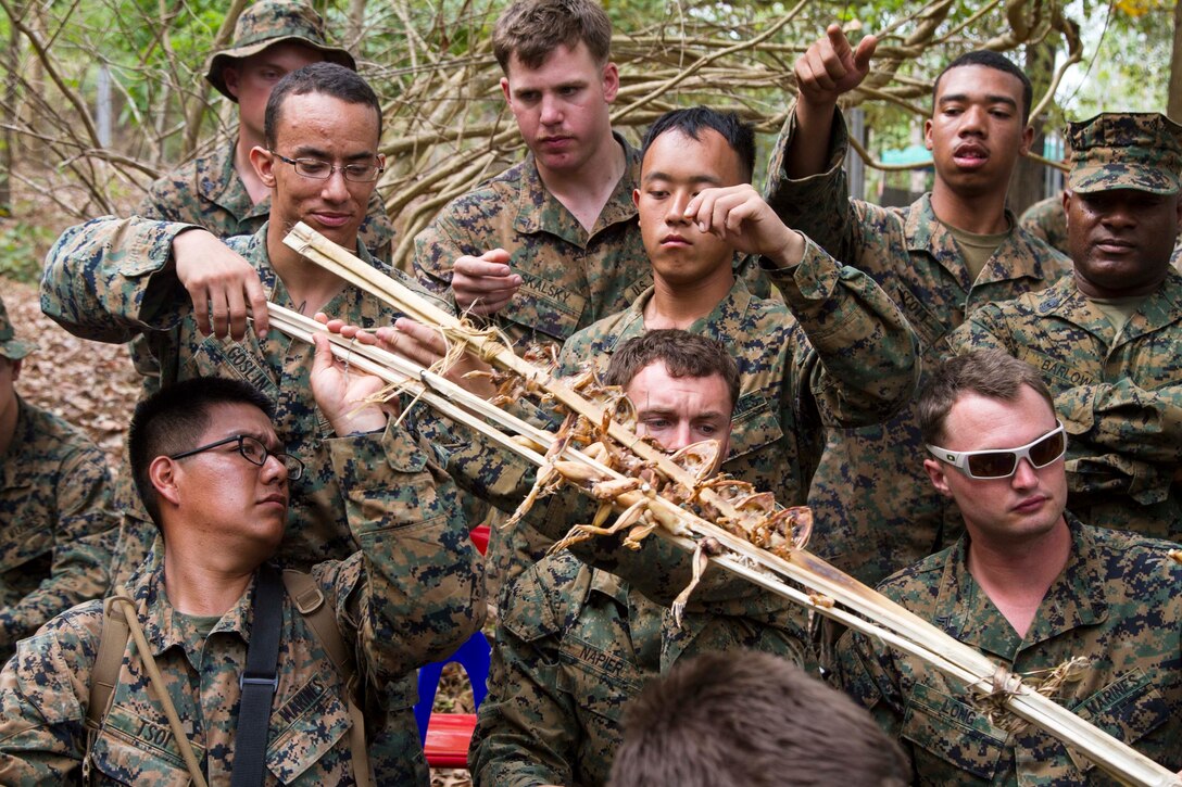 BAN CHAN KREM, Kingdom of Thailand – Marines pass along a piece of bamboo holding cooked frogs during a jungle survival class Feb. 14 at Ban Chan Krem, Kingdom of Thailand during Exercise Cobra Gold. The jungle survival class teaches U.S. Marines basic survival skills that can be used in environments similar to the jungles of Thailand. The course includes knowledge on edible vegetation, water collection, and venomous animal handling. The Marines are with 3rd Battalion, 1st Marine Regiment currently assigned to 3rd Marine Division, III Marine Expeditionary Force under the unit deployment program. (U.S. Marine photo by Lance Cpl. Stephen D. Himes/Released)