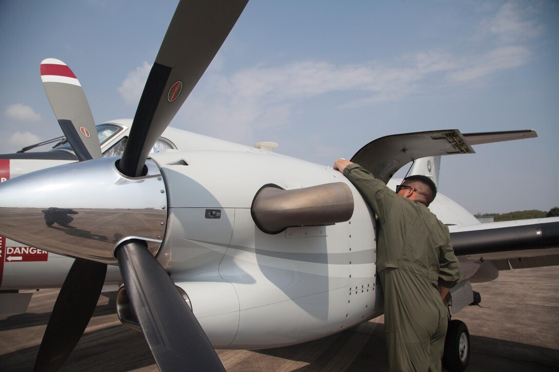 Cpl. Nicholas C. Grasso inspects the UC-12W aircraft in preparation for a flight Feb. 14 at the Utaphao Royal Thai Navy Airfield. Grasso is a transport air crewman with Headquarters and Headquarters Squadron, MCAS Futenma, MCIPAC. (U.S. Marine Corps photo by Cpl. Natalie M. Rostran/Released)