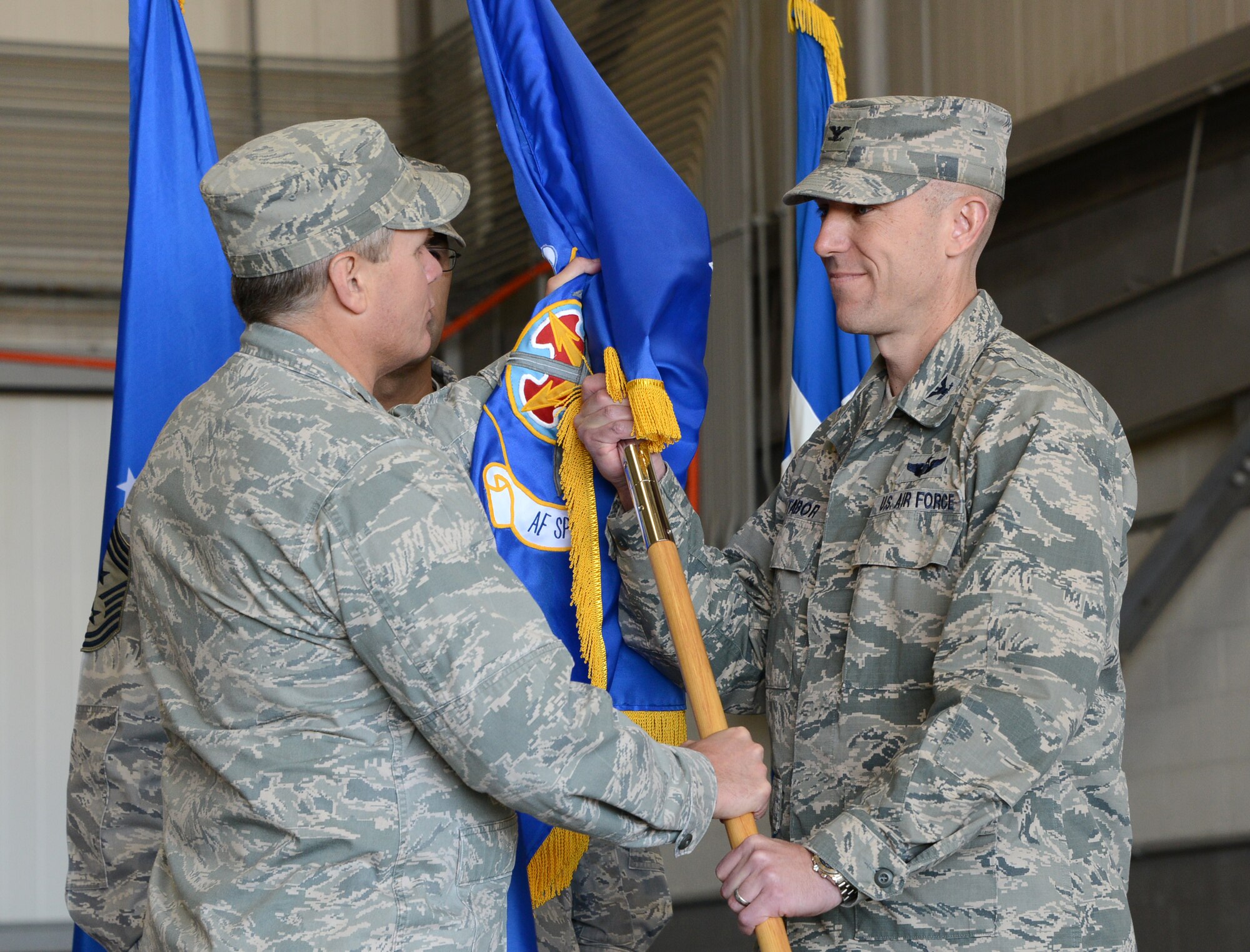 Lt. Gen. Eric Fiel, Air Force Special Operations Command commander, and Col. David Tabor pass the symbolic flag giving Tabor command of the Air Force Special Operations Air Warfare Center during a ceremony at Duke Field, Fla., Feb. 27, 2014. Tabor took command of AFSOAWC which is responsible for doctrine development, education, training, and execution of the command's irregular warfare capabilities. (U.S. Air Force photo by Master Sgt. Steven Pearsall)  