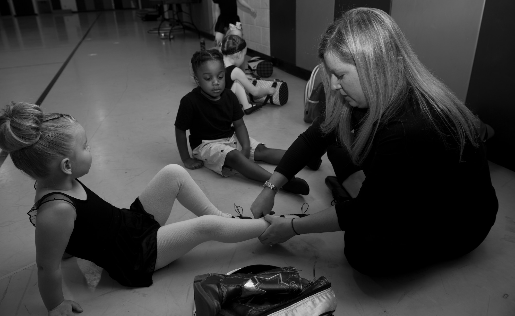 Rebecca Hulun helps her student Sadie Wilcox, daughter of Airman 1st Class Joshua Wilcox, 849th Aircraft Maintenance Squadron, put on her ballet shoes for class at Holloman Air Force Base, N.M., Youth and Teen Center Feb. 25. Hulun is the director and dance teacher of the DS Dance Academy that holds classes in the Youth and Teen Center gymnasium. She teaches a variety of dance classes for students ages toddler to 12 years old. (U.S. Air Force photo by Airman 1st Class Leah Ferrante/Released) 