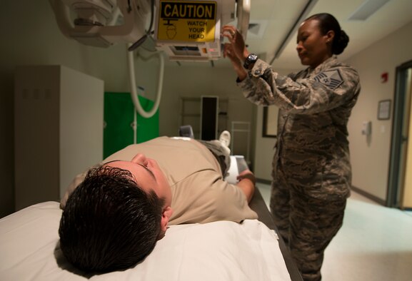 U.S. Air Force Master Sgt. Tracey McLendon, 23d Medical Support Squadron diagnostic imaging flight chief, positions the X-ray tube over Senior Airman Christopher Kingsbury, 23d MDSS diagnostic imaging technologist, at the clinic on Moody Air Force Base, Ga., Feb. 25, 2014. Members of the 23d MDSS radiology clinic train regularly to maintain readiness. (U.S. Air Force photo by Senior Airman Tiffany M. Grigg/Released)