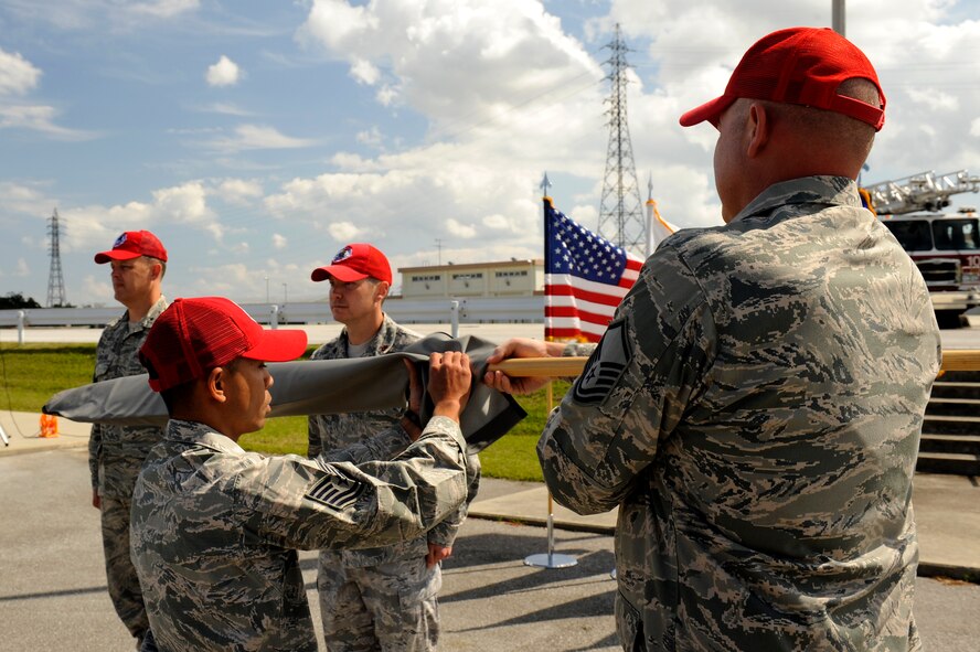 U.S. Air Force Tech. Sgt. Marlon Quitos, Detachment 1, 554th RED HORSE Squadron electrical systems contingency training instructor, sheaths the Detachment 1 guidon during the Silver Flag Stand Down Ceremony on Kadena Air Base, Japan, Feb. 21, 2014. The ceremony marked the official end of the Silver Flag site on Kadena, which has been on Okinawa since 1987. (U.S. Air Force photo by Senior Airman Maeson L. Elleman)