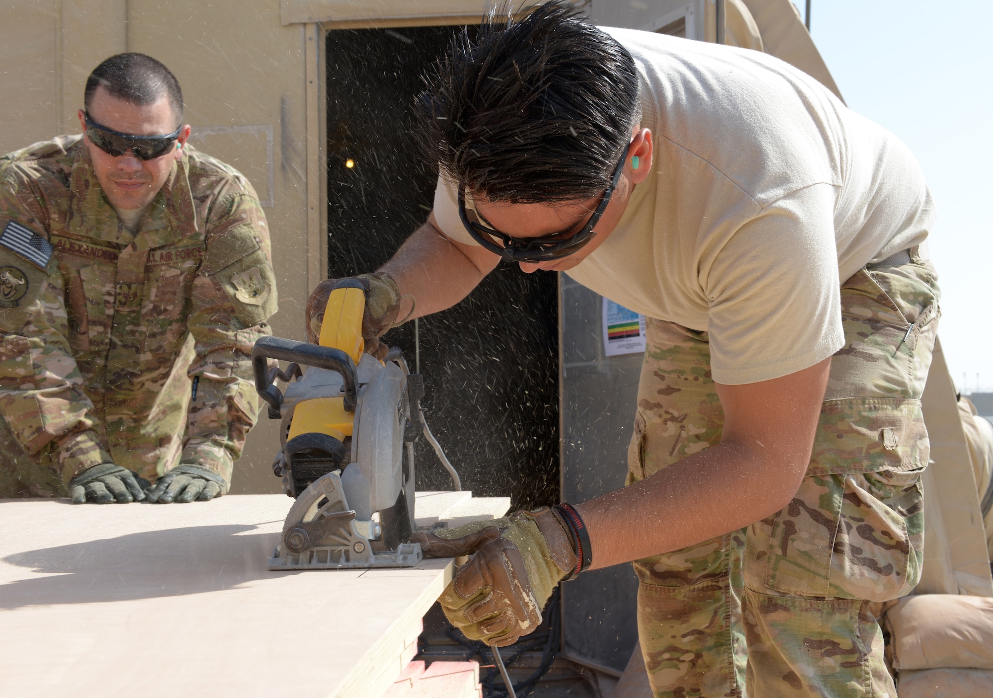 Staff Sgt. Angel Alexander holds a piece of plywood as Airman 1st Class Kristian Martinez-Felix cuts the plywood for the 31st Air Defense Artillery Brigade’s Tactical Operations Center at Al Udeid Air Base, Qatar, Feb. 24, 2014. The 577th Prime BEEF was tasked to construct a TOC to provide a robust and clear audio and visual common operating picture spanning over five nations in the Arabian Gulf region and to meet the security requirements of the 31st ADA Brigade. Both Airmen are 577th EPBS heating, ventilation, and air conditioning technicians. Alexander is deployed from Kadena Air Base, Japan and a Philadelphia, native.  Martinez-Felix is deployed from Grand Forks, N.D., and a Phoenix, native.  (U.S. Air Force photo/Senior Airman Hannah Landeros)