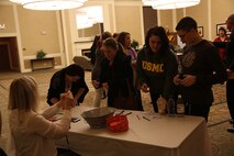 Service members and their spouses sign in and pick up raffle tickets at the beginning of a spouse meet and greet aboard Camp Lejeune, N.C., Feb. 25, 2014. More than 100 Marines, sailors and their spouses from throughout the 2nd Marine Logistics Group attended the event.  (U.S. Marine Corps photo by Lance Cpl. Shawn Valosin)