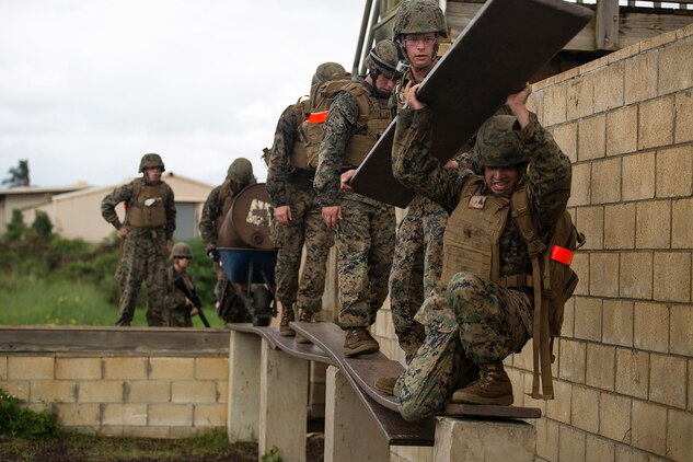 Cpl. Zedekiah Delacruz (right), an electronic maintenance specialist with 1st Battalion, 12th Marine Regiment, grabs ahold of a board as he attempts to create a safe path along the obstacle during a leadership reaction course at Boondocker Training Area aboard Marine Corps Base Hawaii, Feb. 25, 2014. The Marines were participating in Corporals Course and completed a case study that took them through several training exercises based off true scenarios Gunnery Sgt. Timothy C. Tardif experienced during Operation Iraqi Freedom, April 12, 2003. Three squad-sized teams participated in a leadership reaction course, and exercises at Boondocker Training Area to include the obstacle course and military operations on urban terrain facility and a 100-meter swim at the base pool. At the conclusion of the case study, the Marine gathered at Dewey Square to listen to Tardif explain the challenges he faced as a corporal on the battlefield and how he overcame them.  (U.S. Marine Corps photo by Lance Cpl. Matthew Bragg)