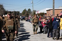 A Marine with 2nd Maintenance Battalion, Combat Logistics Regiment 25, 2nd Marine Logistics Group gives high-fives to students outside of Carolina Beach Elementary School during a nine-mile hike through Carolina Beach, N.C., Feb. 27, 2014. Marines and sailors with the company hiked with approximately 70 pounds of gear at a pace of three miles per hour, stopping at historical locations for professional military education lectures. (U.S. Marine Corps photo by Lance Cpl. Shawn Valosin)