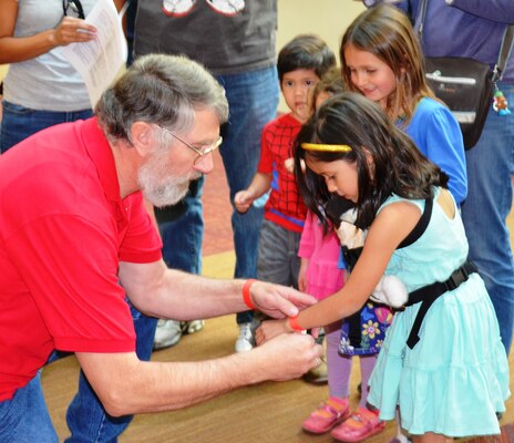 ALBUQUERQUE, N.M., --Greg Everhart, district archeologist, assisted a young participant with her wristband during the S.T.E.M Festival events, Feb. 22, 2014.