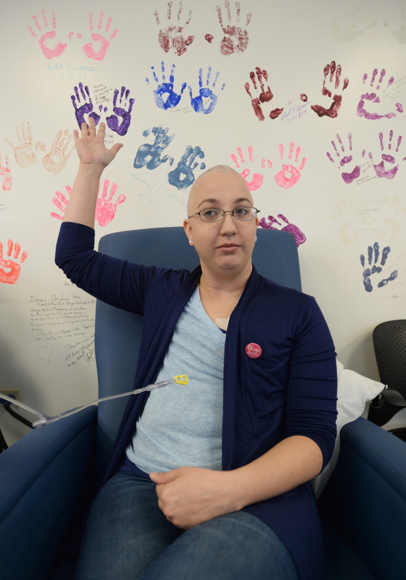 Staff Sgt. Amanda Dick, 15th Medical Support Squadron patient flight, poses in front of a wall of painted hands during her chemotherapy treatment at Tripler Army Medical Center, Honolulu, Hawaii, Feb. 26, 2014. The hands are of cancer patients that were treated at the medical center. Since being diagnosed with breast cancer in October 2013, Dick has finished one-of-two rounds of chemotherapy, and is expected to be done with treatment in April. (U.S. Air Force photo/Staff Sgt. Alexander Martinez)