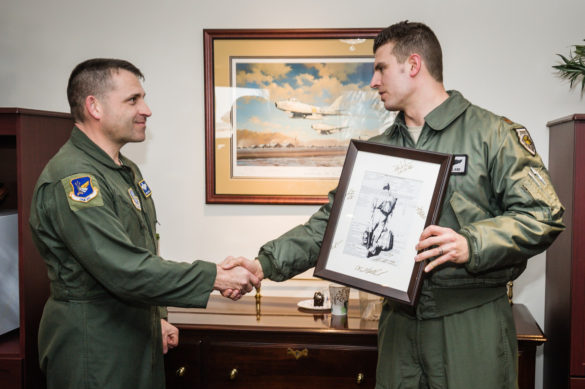 Maj. Kiel Gilliland, 57th Weapons Squadron aircraft commander, right, congratulates Chief Master Sgt. Louis Orrie, 305th Air Mobility Wing command chief, on the completion of his fini-flight Feb. 25, 2014, at Joint Base McGuire-Dix-Lakehurst, N.J. Orrie was present with a copy of his fini-flight orders signed by the crewmembers aboard the C-17 Globemaster III. (U.S. Air Force photo by Russ Meseroll/Released)