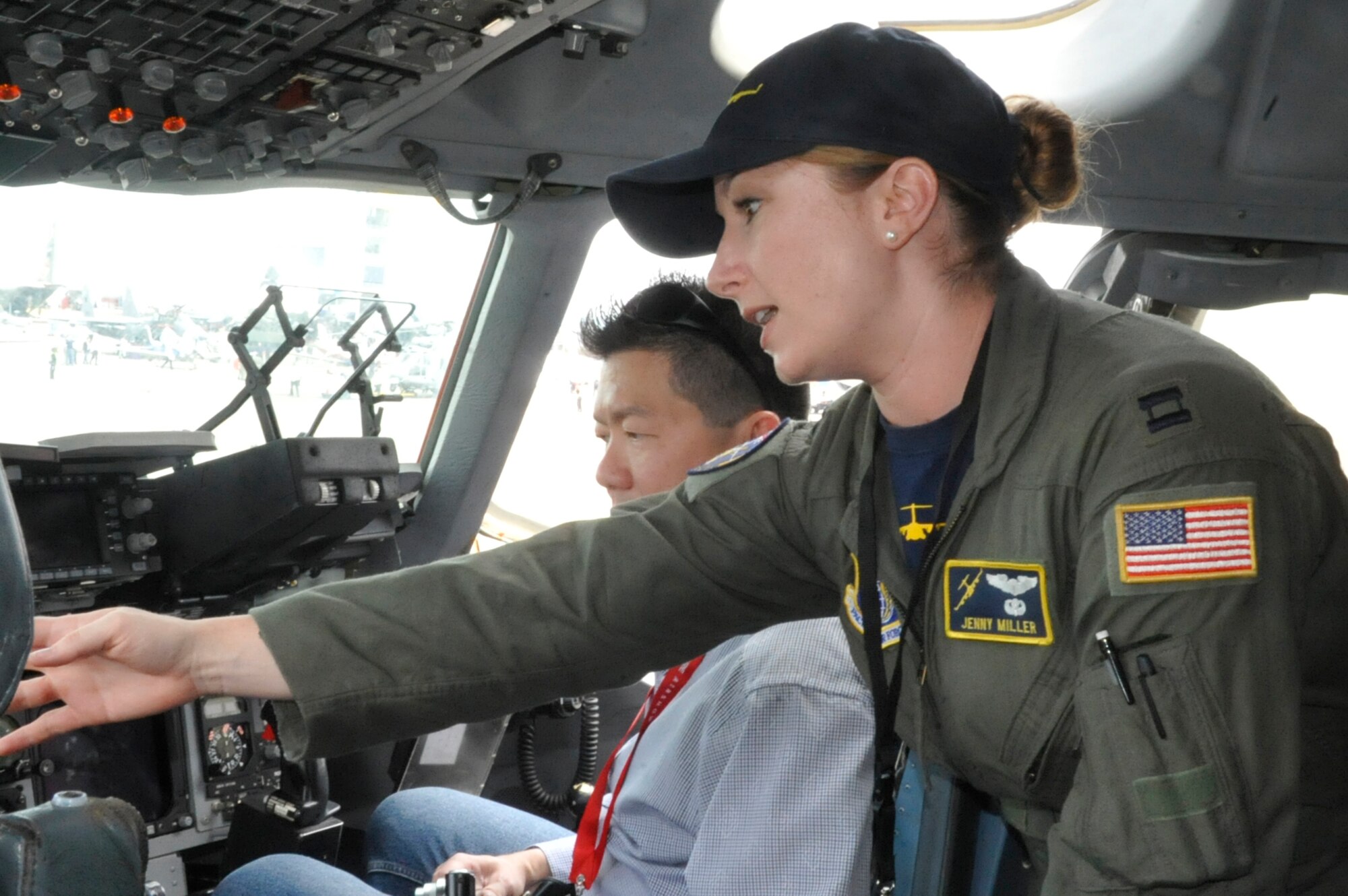 Capt. Jenny Miller, Pacific Air Forces instructor pilot at Joint Base Pearl Harbor-Hickam, Hawaii, explains her aircraft's capabilities to visitors in the cockpit of a C-17 Globemaster III at the 2014 Singapore International Airshow, Feb. 11, 2014. Miller has been flying since 2006 and has over 2,000 flying hours in the C-17, half of which were in a combat zone. (U.S. Air Force photo/Capt. Tamara Fischer-Carter)