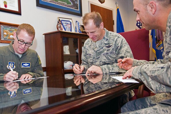 Col. Corey Martin, 60th Air Mobility Wing commander, Col. Matt Burger, 349th Air Mobility Wing commander, and Col. Martin Chapin, 621st Contingency Response Wing commander sign pledges Feb. 18 to kick off the Air Force Assistance Fund campaign. (U.S. Air Force photo/Senior Airman Madelyn Brown)