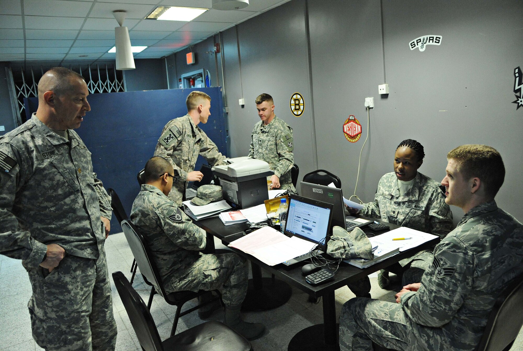 Army Maj. Avraham Stone (left), and SPC Rhonda Bush (second from right), talk to Senior Airman Brandon Burgess, 386th Expeditionary Force Support Squadron linen exchange, about tax-filing procedures, Wednesday, at undisclosed location in Southwest Asia.  Stone, a judge advocate and tax-center officer in charge from a nearby Army installation, and his team of three Soldiers spent the day helping members of the 386th Air Expeditionary Wing file their taxes for 2013.  The free service will be offered again, March 26, at the Drop Zone recreational facility and is available for all military members assigned to the 386th AEW.  (U.S. Air Force photo by Senior Airman Desiree Moye)
