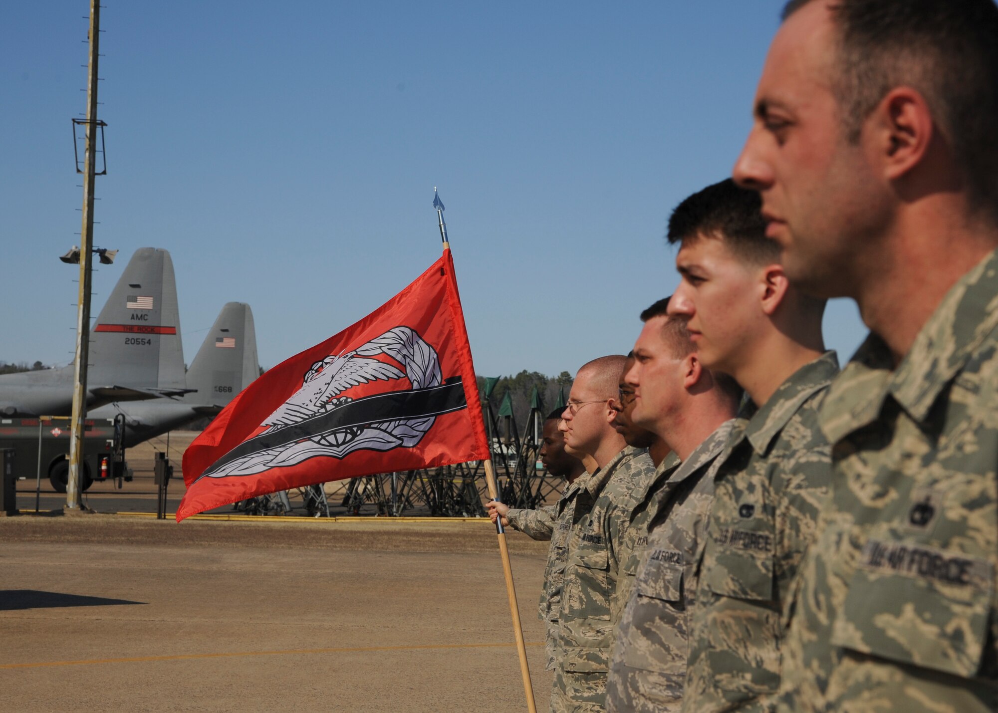 Airmen from the 19th Logistics Readiness Squadron stand during a brief on the significance of the Port Dawg 3K Feb. 21, 2014, at Little Rock Air Force Base, Ark. The annual Port Dawg 3K event involves aerial porters from all over the world running in formation to honor and show support for fallen comrades. (U.S. Air Force photo by Airman 1st Class Harry Brexel)