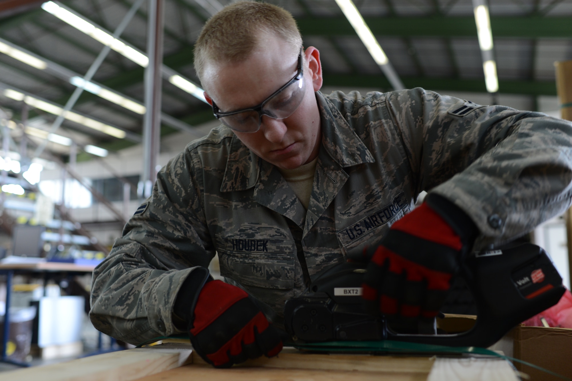 U.S. Air Force Airman 1st Class Frank Houdek, 52nd Logistics Readiness Squadron packing and crating specialist from Tucson, Ariz., secures a crate with metal bands at Spangdahlem Air Base, Germany, Feb. 25, 2014. Traffic Management Office Airmen complete the banding process to ensure the crate will not fall apart during shipping. (U.S. Air Force photo by Senior Airman Gustavo Castillo/Released)