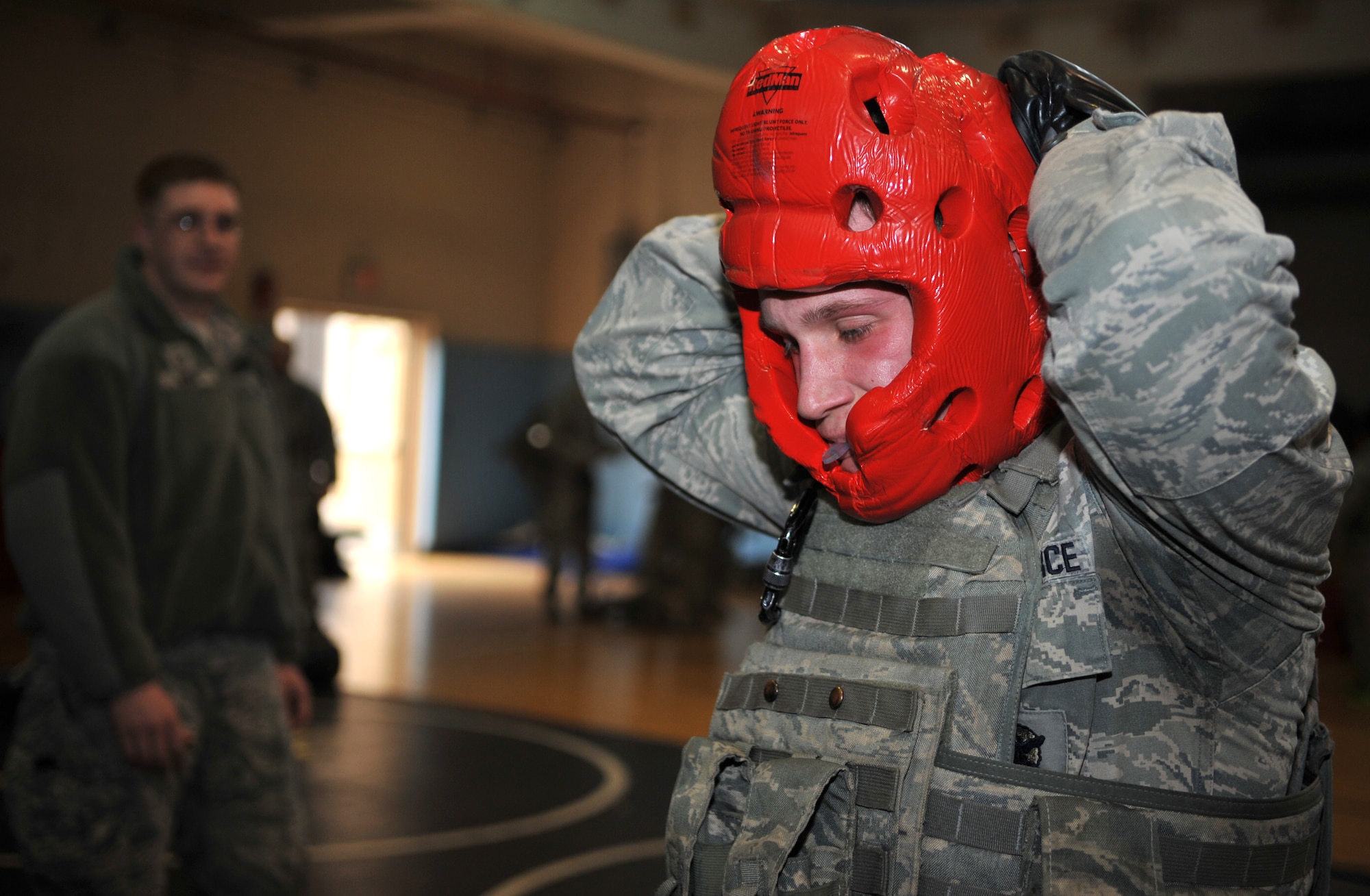 A member of the 51st Security Forces Squadron secures his protective headgear prior to a combatives bout during a House of Pain training event in the fitness center at Osan Air Base, Republic of Korea, Feb. 27, 2014. The confidence course featured several different stations that defenders rotated between every 90 seconds. (U.S. Air Force photo/Airman 1st Class Ashley J. Thum)