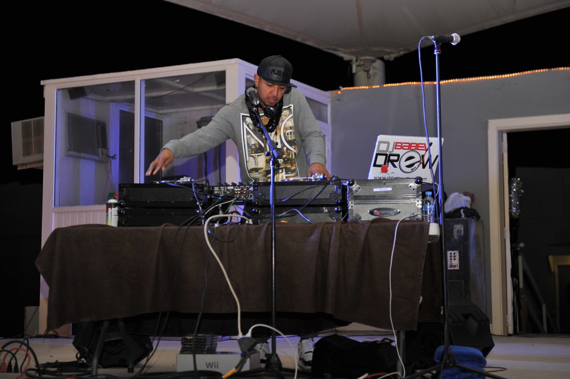 DJ Babey Drew plays music during the New Year’s Eve performance at the 379th Air Expeditionary Wing, Southwest Asia, Dec. 31, 2013. DJ Babey Drew, Comedienne Eliza Sherzinger, winner of NBC's Last Comic Standing competition, brought her brand of humor. The Farm, a country music band that merges different genres into a unique sound. The Farm stopped playing prior to the raising of the ball at midnight. Soon after the New Year was celebrated The Farm and DJ Babey Drew entertained until 2 a.m.(U.S. Air Force photo by Master Sgt. David Miller)