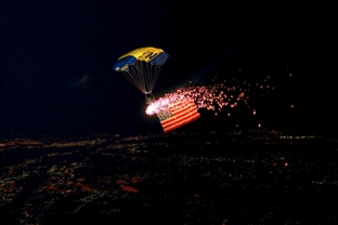 U.S. Navy 1st Class Vic Maldonado presents the American flag under the lights of a pyrotechnic display at Qualcomm Stadium in San Diego, Calif., Dec. 30, 2013. Maldonado is a member of the U.S. Navy parachute demonstration team, the Leap Frogs, which performs aerial parachute demonstrations around the nation in support of Naval Special Warfare and Navy recruiting. 