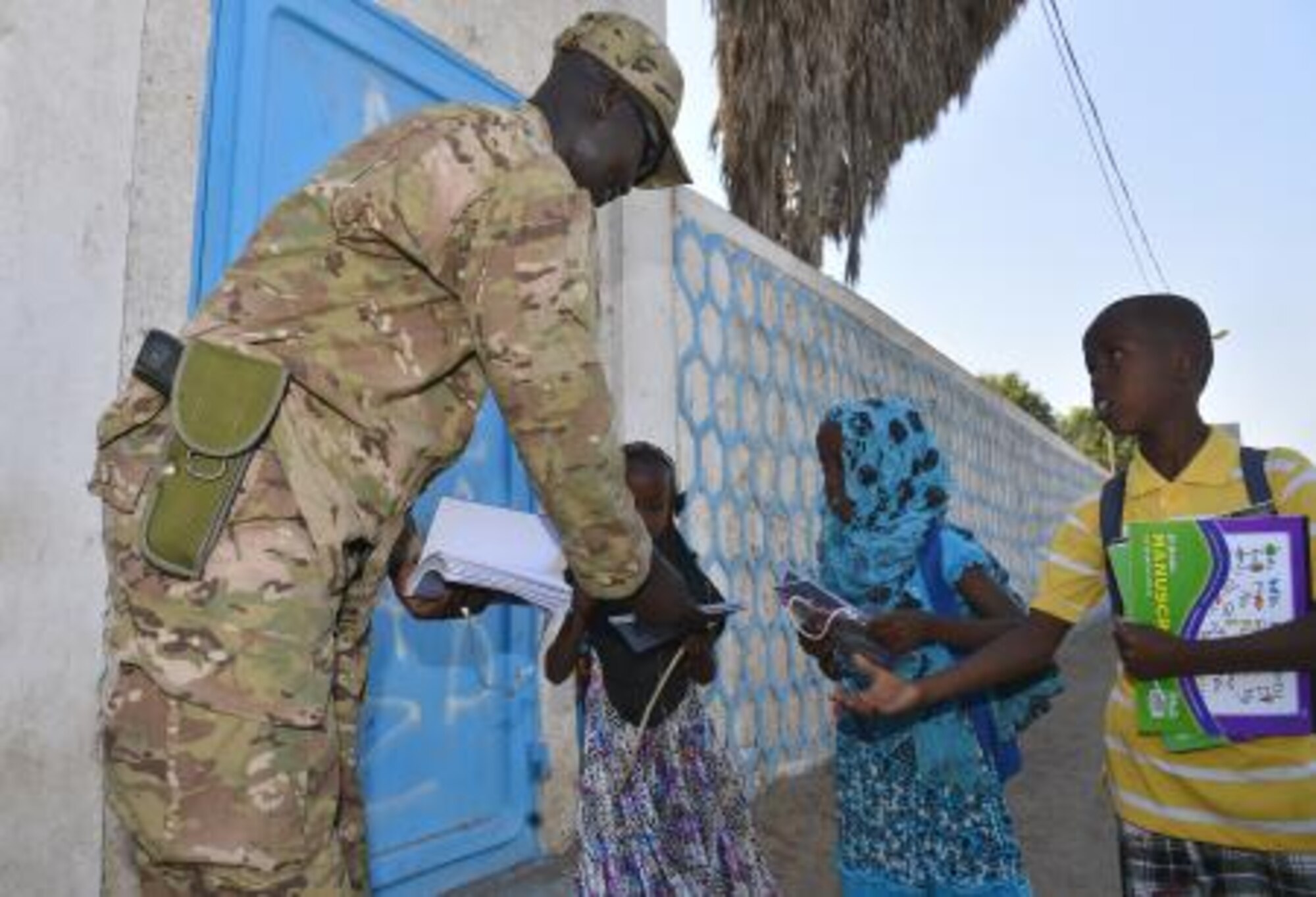 Staff Sgt. Deng Pour, Combined Joint Task Force-Horn of Africa, non-commissioned officer in charge of religious affairs, gives school supplies to local children in Djibouti Dec. 15, 2013. Pour’s goal while in Africa is to give back to his peers and country. (U.S. photo by Staff Sgt. Antoinette Gibson)

