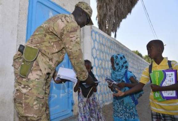 Staff Sgt. Deng Pour, Combined Joint Task Force-Horn of Africa, non-commissioned officer in charge of religious affairs, gives school supplies to local children in Djibouti Dec. 15, 2013. Pour’s goal while in Africa is to give back to his peers and country. (U.S. photo by Staff Sgt. Antoinette Gibson)

