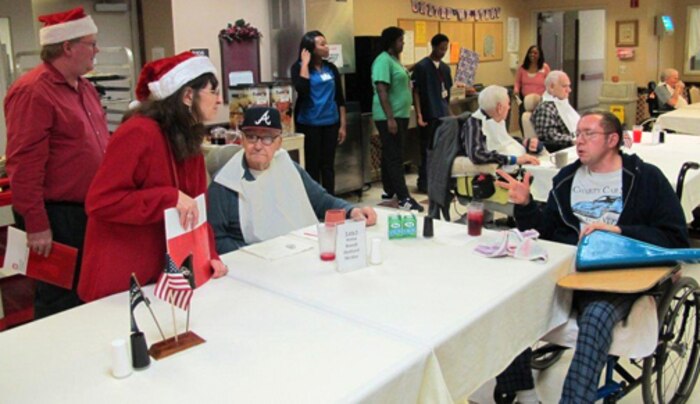 Huntsville Center employees visited residents of the Floyd E. "Tut" Fann Alabama State Veterans Home, Huntsville, Ala. Dec. 20 following the Holiday Town Hall gathering at the University of Alabama-Huntsville Student Center. Huntsville Center employees delivered more than 150 gift bags, put together with donations by the Center's work force, to the residents. Members of the Huntsville Center work force came together to form a Holiday Choir to sing at the town hall and outreach events.