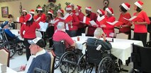Huntsville Center employees visited residents of the Floyd E. "Tut" Fann Alabama State Veterans Home, Huntsville, Ala. Dec. 20 following the Holiday Town Hall gathering at the University of Alabama-Huntsville Student Center. Huntsville Center employees delivered more than 150 gift bags, put together with donations by the Center's work force, to the residents. Members of the Huntsville Center work force came together to form a Holiday Choir to sing at the town hall and outreach events.