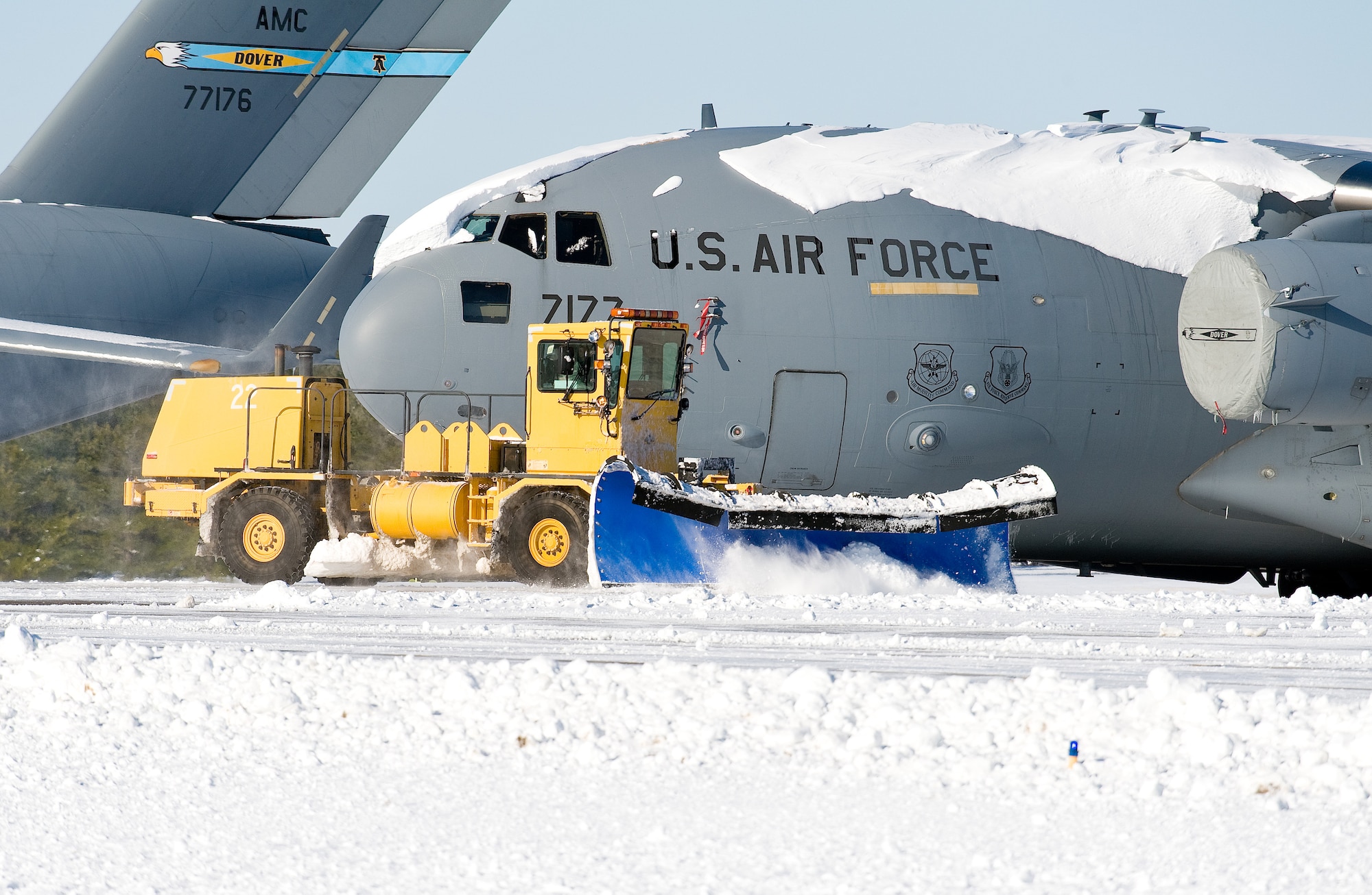 A snow plow from the 436th Civil Engineer Squadron clears snow in front of a snow-covered C-17A Globemaster III Jan. 3, 2014, at Dover Air Force Base, Del. As snow fell and even after, the base continued normal operations as Team Dover personnel initiated snow removal throughout the base. (U.S. Air Force photo/Roland Balik)