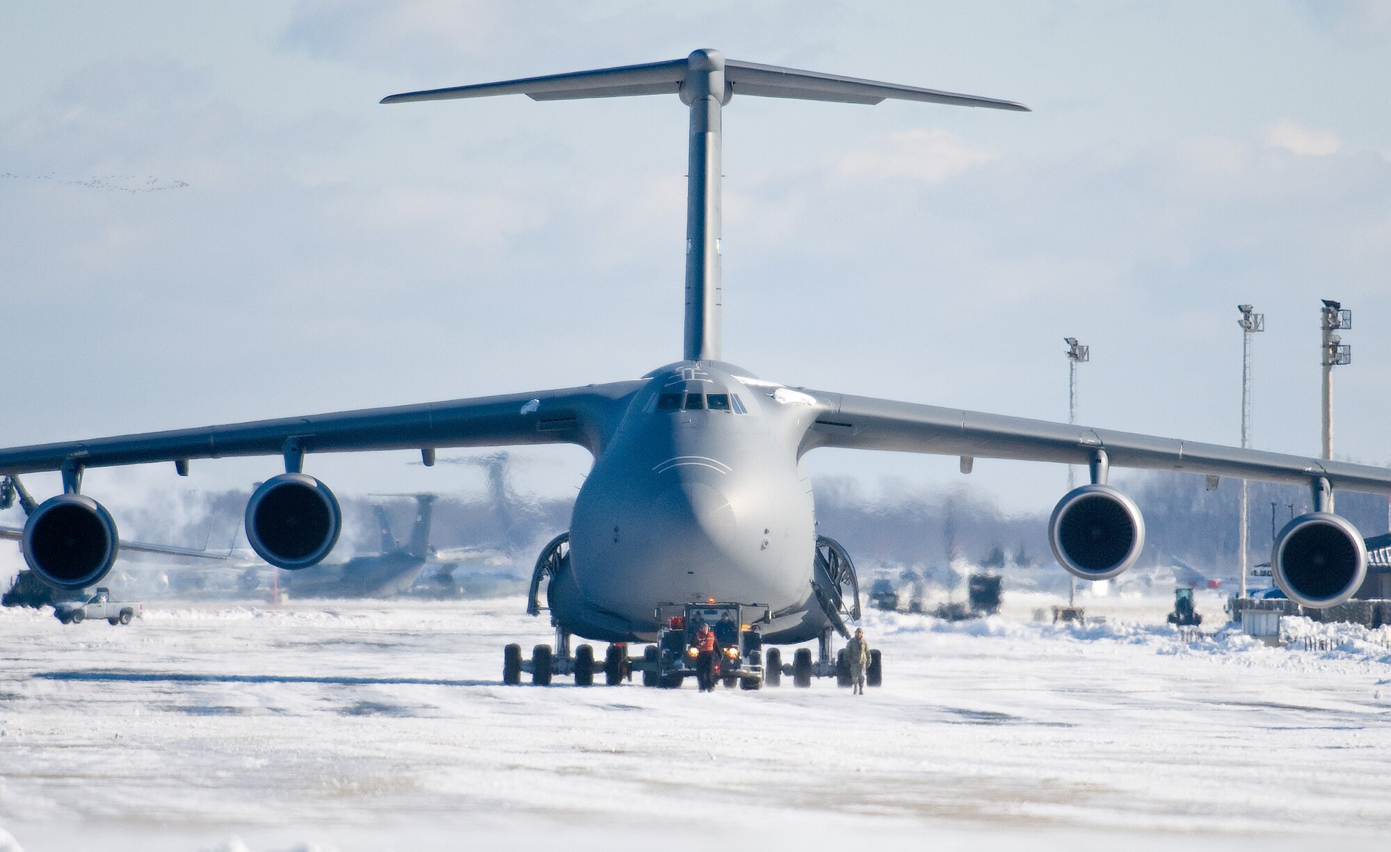 Team Dover aircraft maintenance personnel tow a C-5M Super Galaxy down the flight line Jan. 3, 2014, at Dover Air Force Base, Del. The tow team crew pushed the aircraft out of the wash rack hangar after the snow storm passed. (U.S. Air Force photo/Roland Balik)