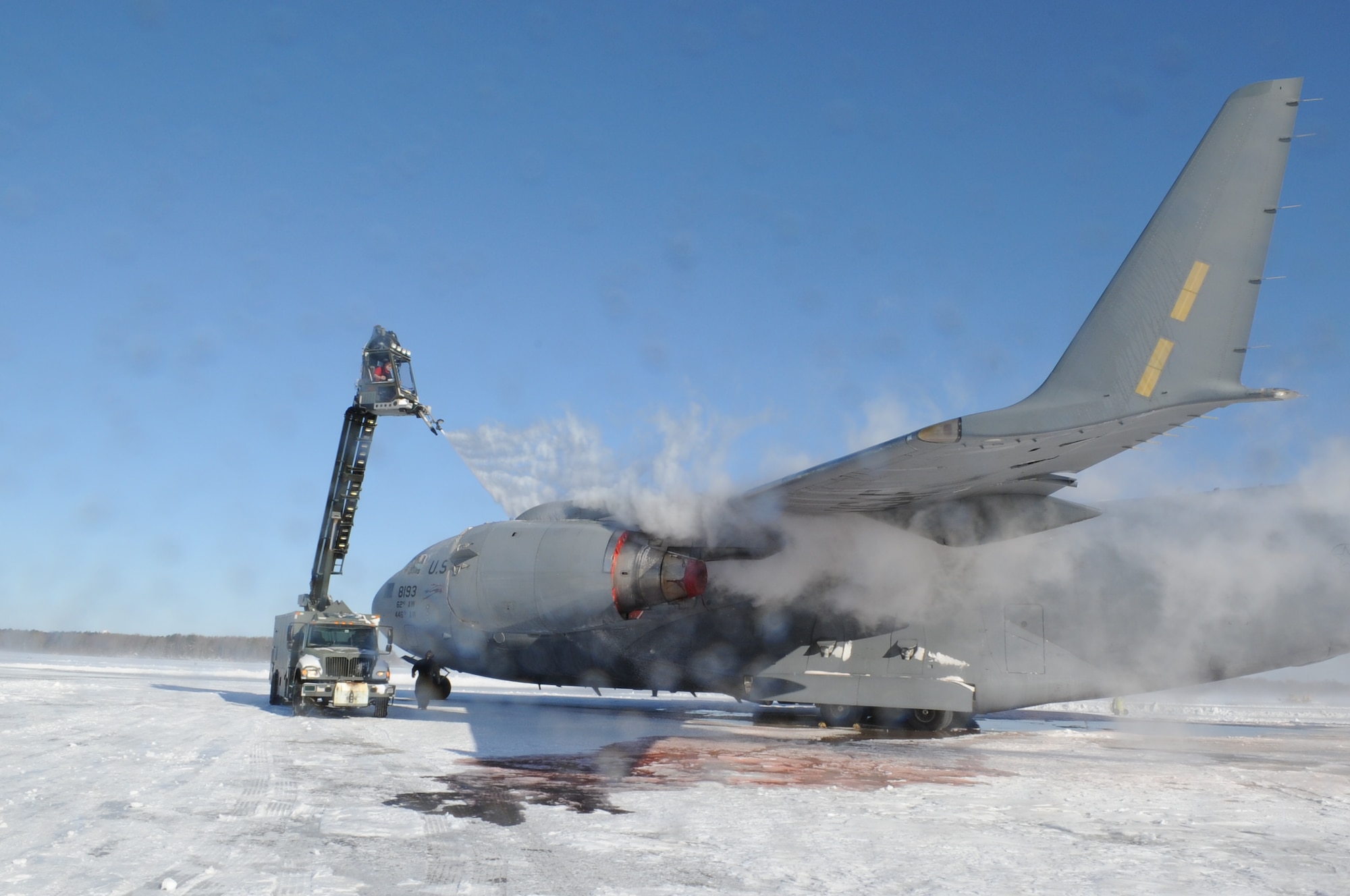 Members from the 736th Aircraft Maintenance Squadron spray deicing fluid onto the wing of a C-17A Globemaster III, based at Joint Base Lewis-McChord, Wash., Jan. 3, 2014, at Dover Air Force Base, Del. The deicing fluid removes built-up ice and snow from the aircraft in order to make it flight-ready. The photographer and camera were hit by some of this fluid as it was blown off of the plane by the strong winds. (U.S. Air Force photo/Airman 1st Class Zachary Cacicia) 