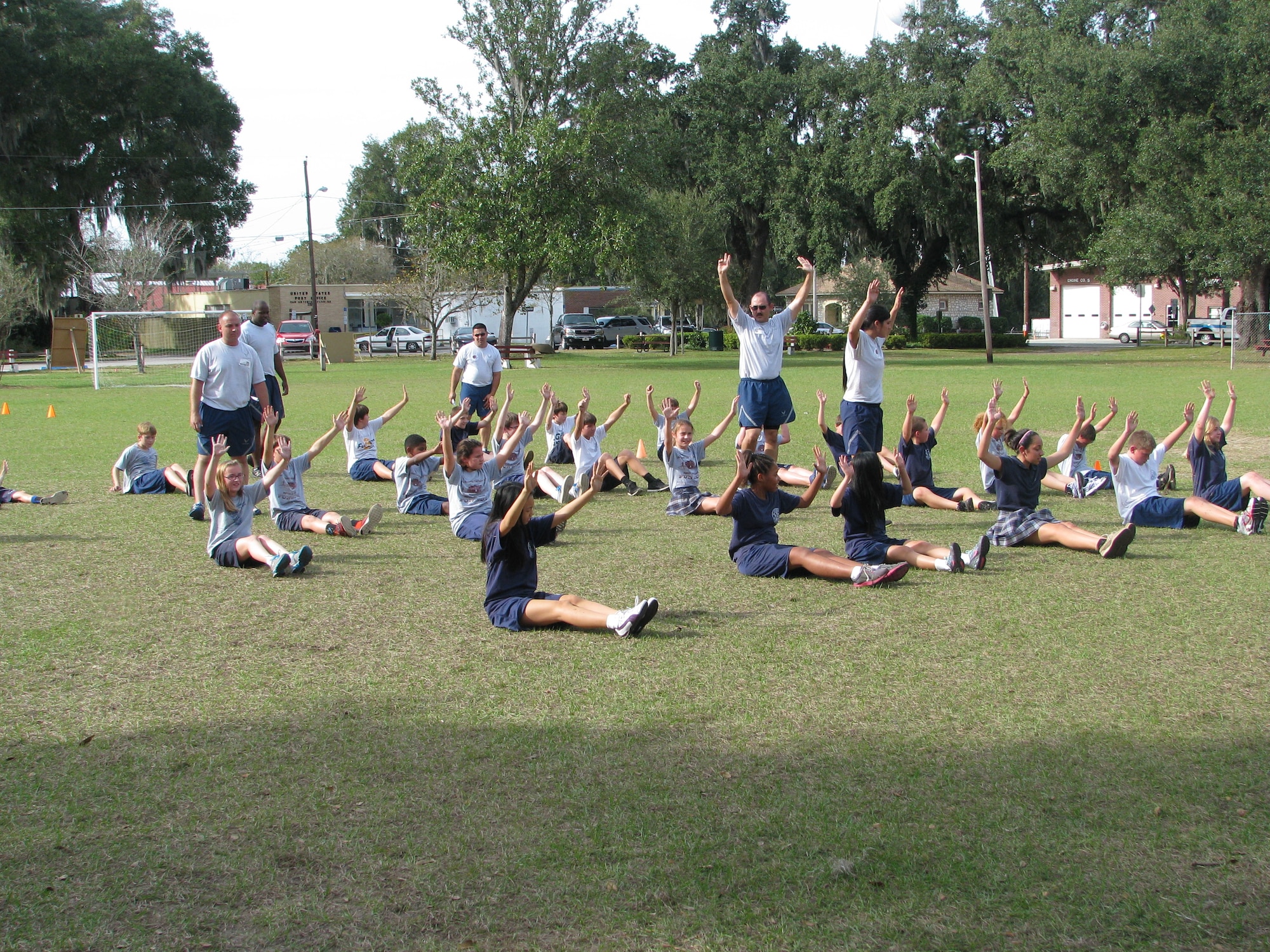 Members of the 6th Communication Squadron teach children from Saint Anthony Catholic School how to do pyramid push-ups during physical education Dec. 5, 2013 in Tampa, Fla. Seven volunteers, including a former U.S. Air Force Basic Military Training instructor, volunteered to perform a modified version of BMT physical training exercises with fifth through eighth graders. (Courtesy photo)