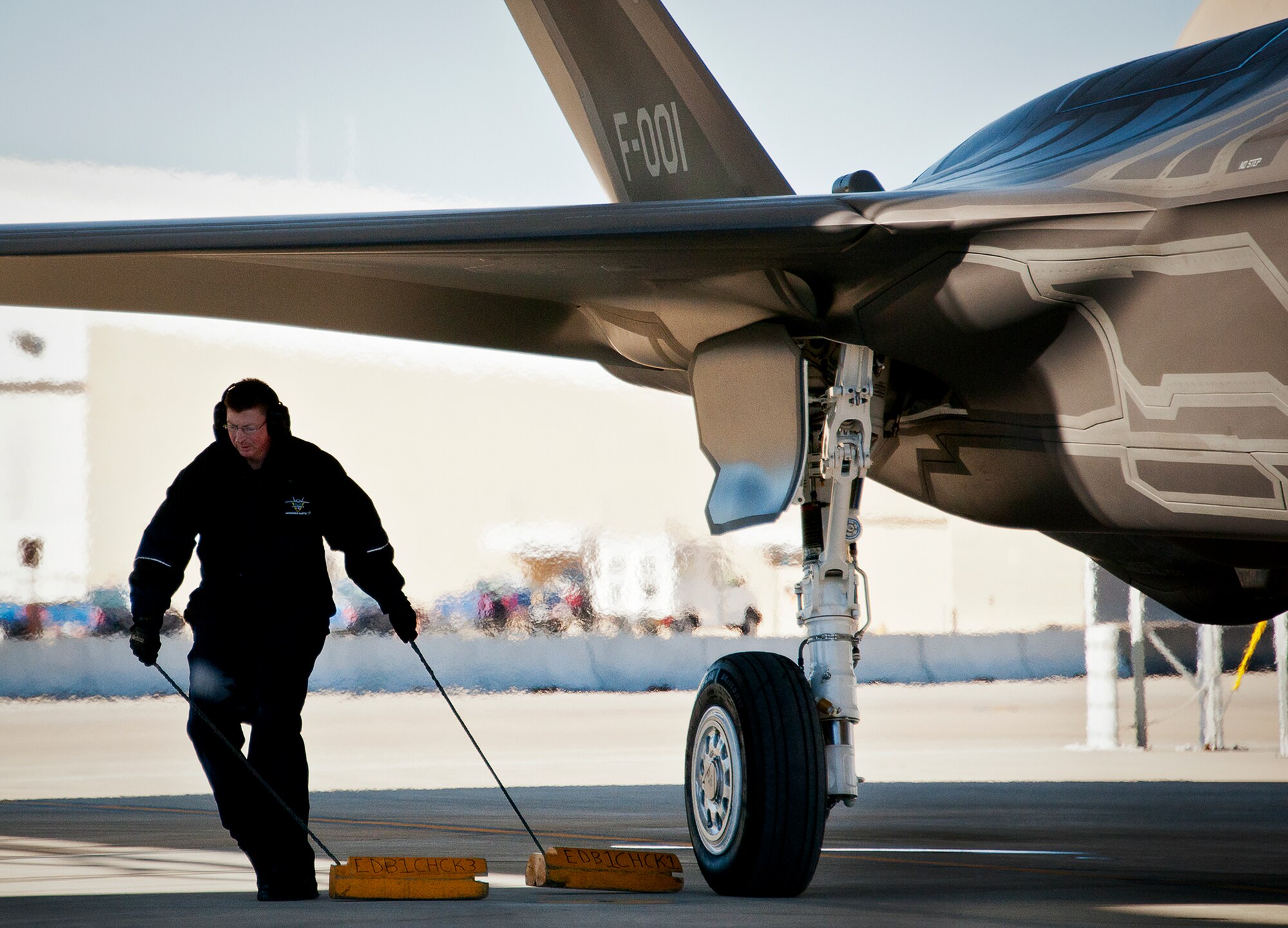 A Lockheed Martin maintainer pulls the chocks from a Royal Netherlands Air Force F-35A Lightning II prior to a sortie at Eglin Air Force Base, Fla.  The RNLAF completed their first joint strike fighter flying sortie Dec. 18. (U.S. Air Force photo/Samuel King Jr.)