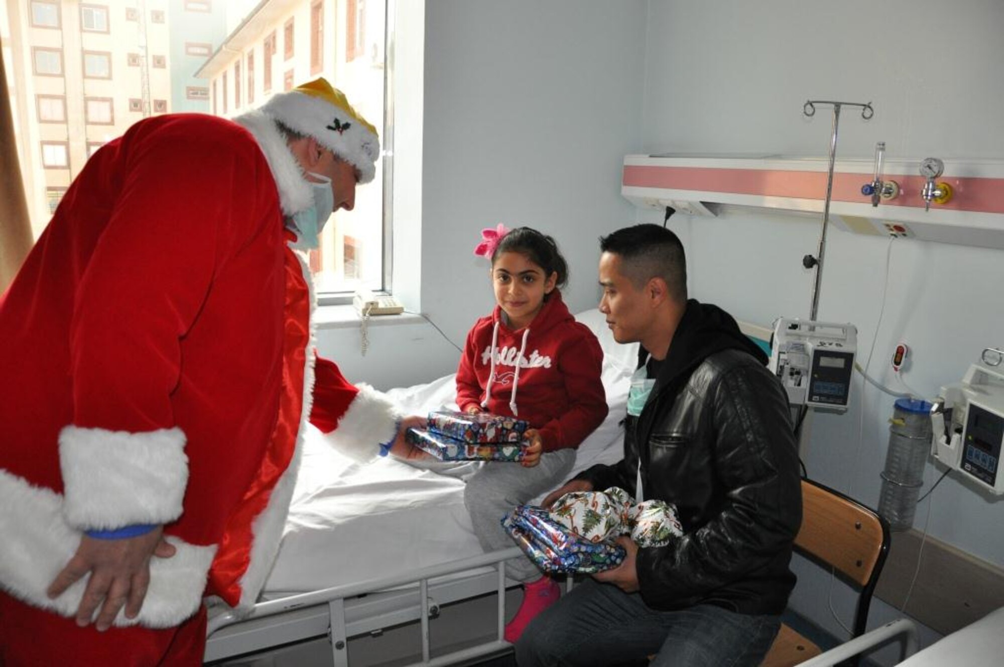 Tech. Sgt. Siam Bean (right), 425th Air Base Squadron Command Section commander’s administrator, gives a toy to a Turkish child with  Murat Özçelik, a Vinnell-Brown and Root employee, dressed as Santa Claus at an Izmir children’s hospital Dec. 23, 2013 at Izmir, Turkey.  Izmir community members visited the hospital as part of a toy drive by the chaplain’s office to provide the children toys and gifts. More than 180 children received gifts. (U.S. Air Force photo by Tanju Varlıklı/Released)
