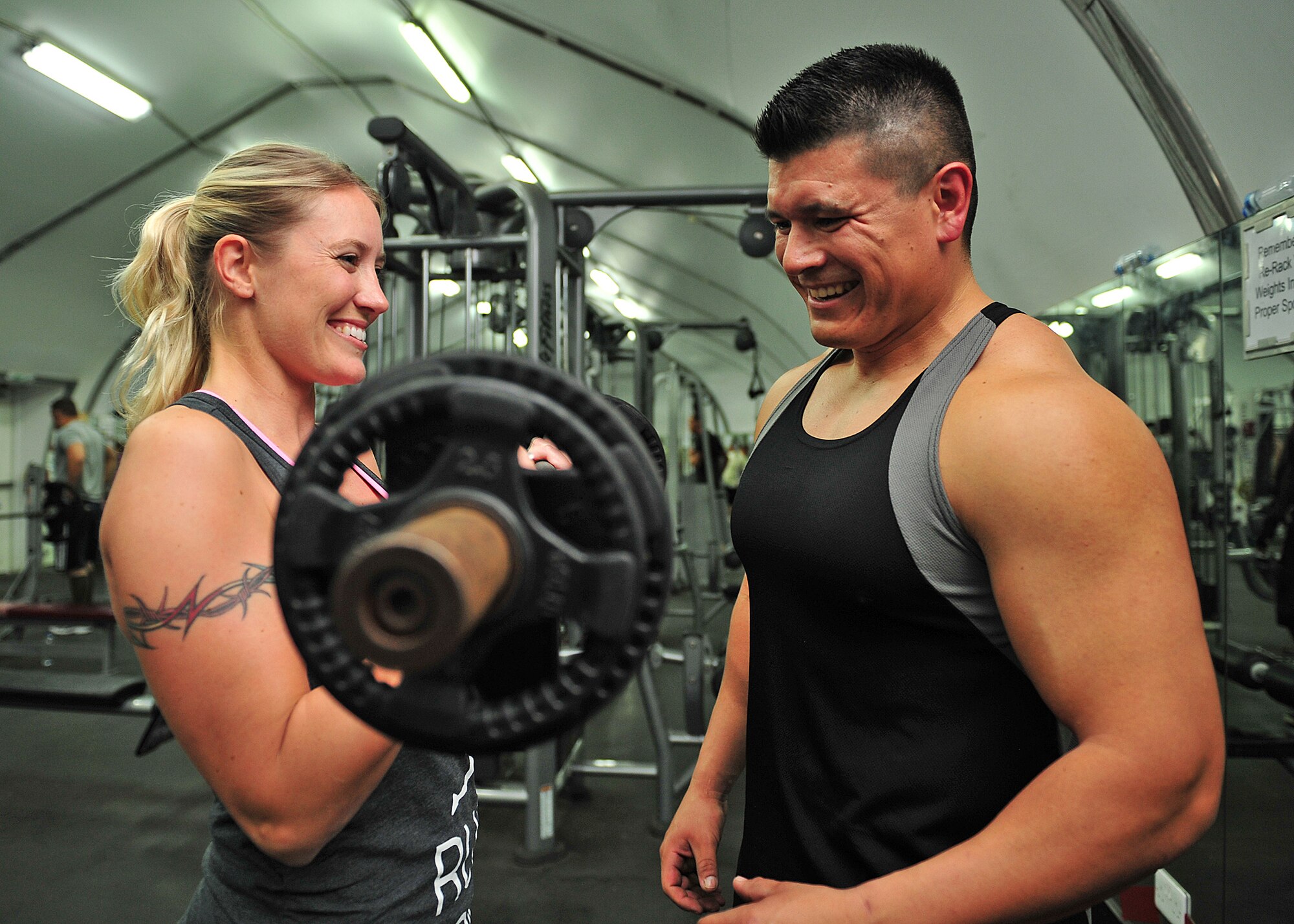 Capt. Ezekiel "E.Z." Duran, a physiologist with the 380th Expeditionary Medical Group, gives workout tips to Capt. Holly Brauer, 380th Air Expeditionary Wing chief of protocol, at an undisclosed location in Southwest Asia, Jan. 1, 2014. (U.S. Air Force photo by Staff Sgt. Michael Means/Released)
